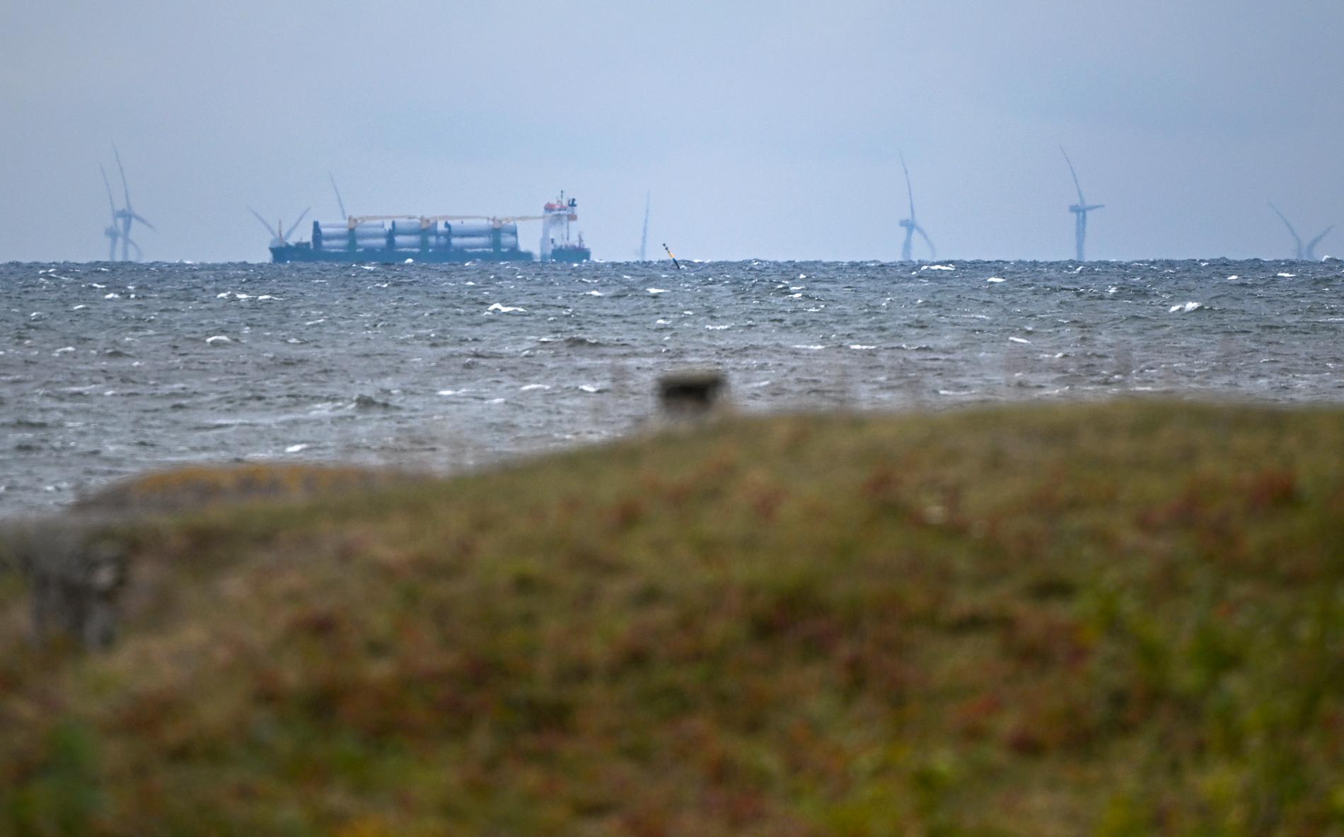 Ett lastfartyg lastat med torn till vindkraftverk passerar medan de 188 meter höga vindkraftverken på den danska delen av Kriegers Flak.