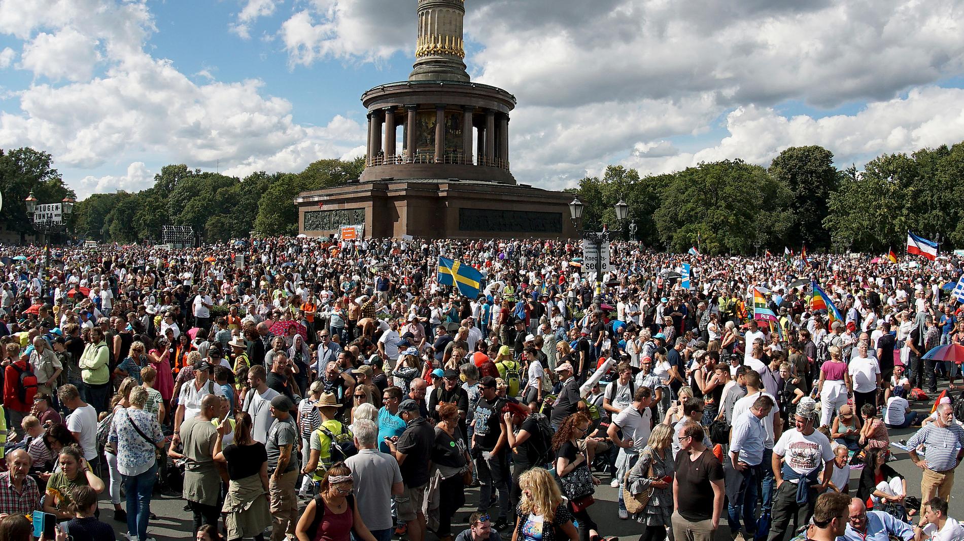 En svensk flagga vajar i vinden framför Siegessäule i Berlin, där tusentals personer samlades för en protest mot de tyska coronarestriktionerna i augusti i år.