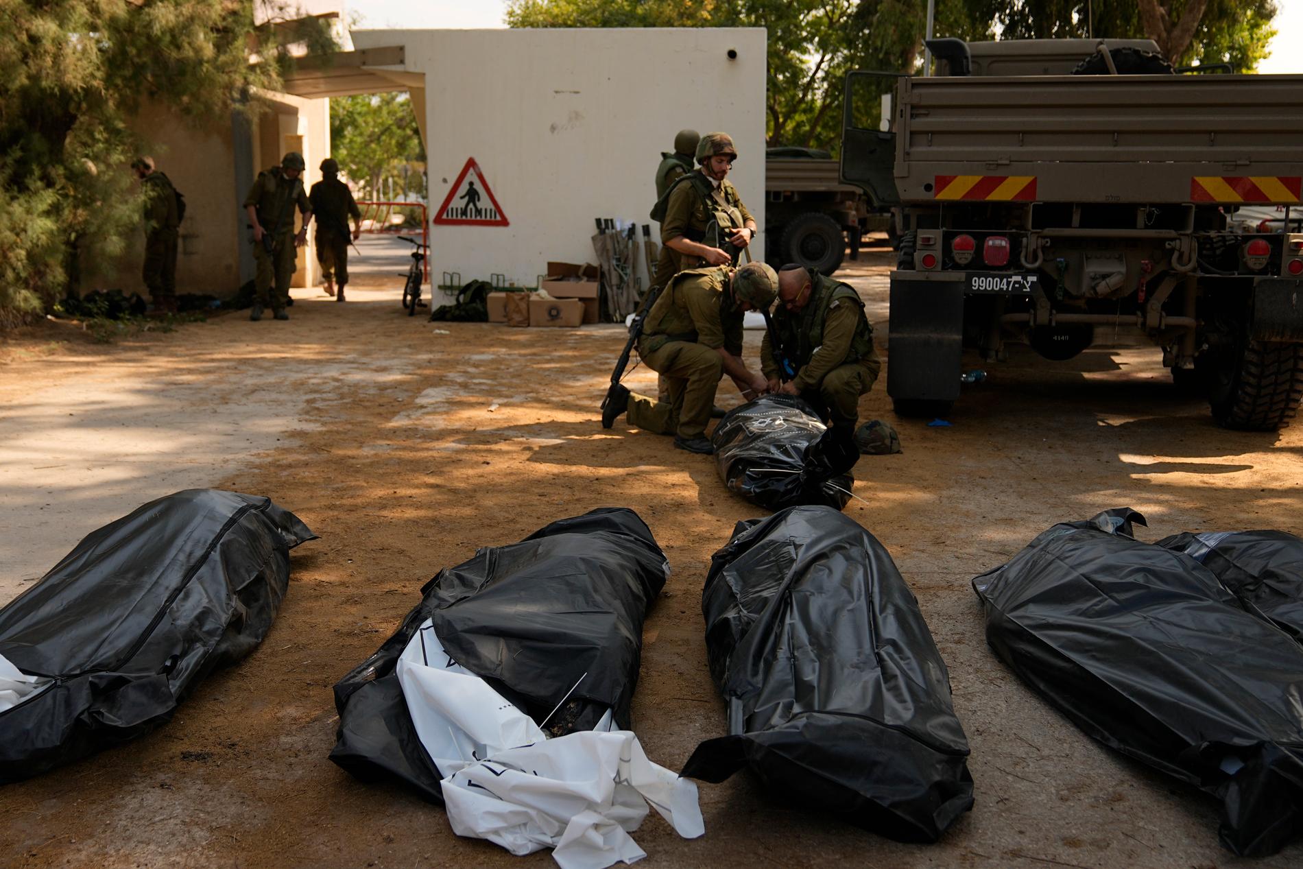 Döda människor som lagts i liksäckar. De ligger på marken i kibbutzen Kfar Aza på tisdagen den 10 oktober. 
