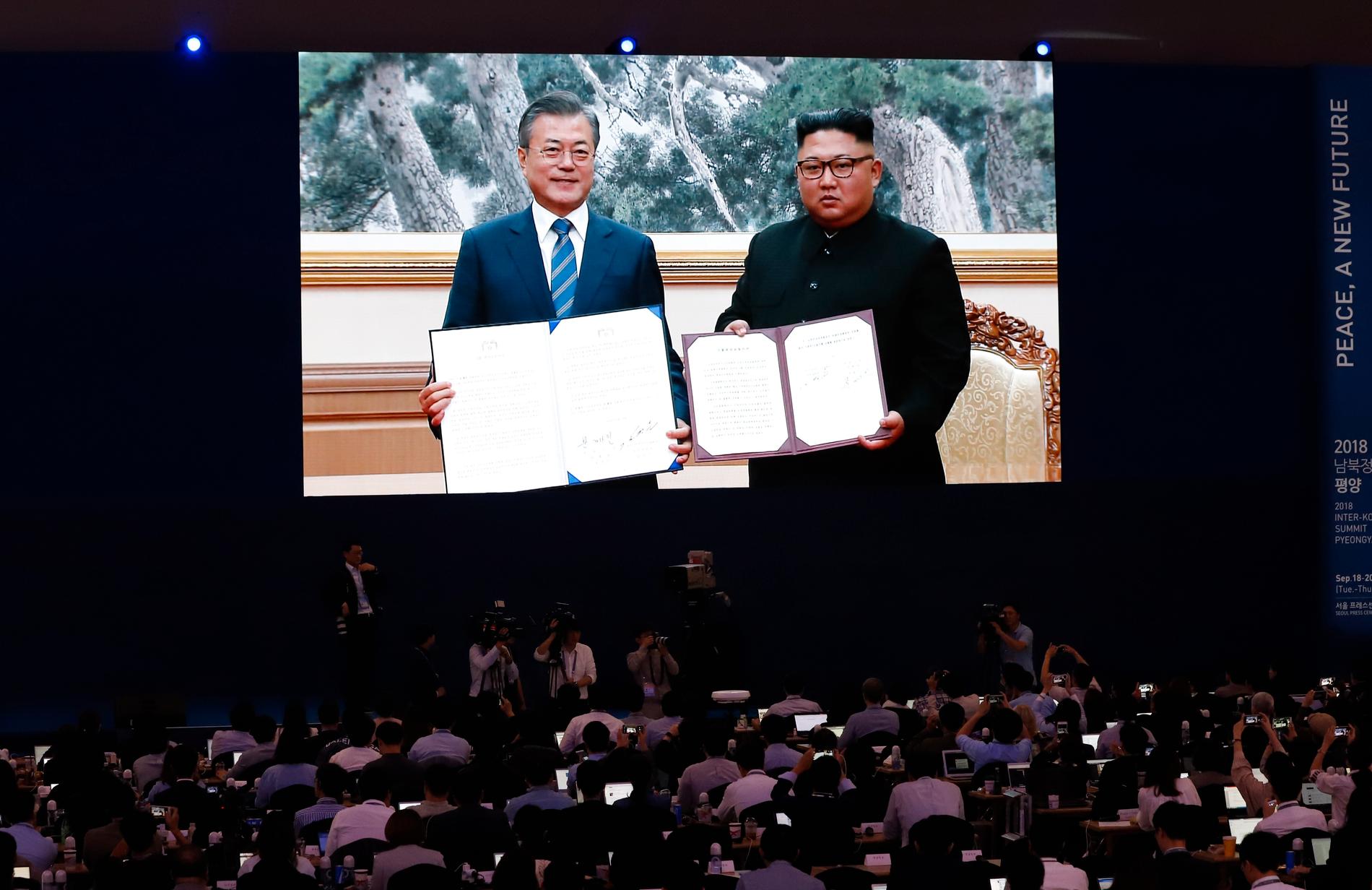 Journalister tittar på en stor skärm när Sydkoreas president Moon Jae-In och Nordkoreas diktator Kim Jong-Un visar upp undertecknade dokument efter onsdagens överläggningar.