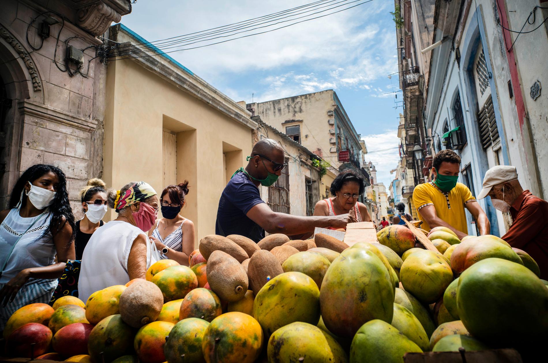 Havannabor köper mango på en gata i Kubas huvudstad. Landets myndigheter har infört krav på att bära munskydd utomhus.