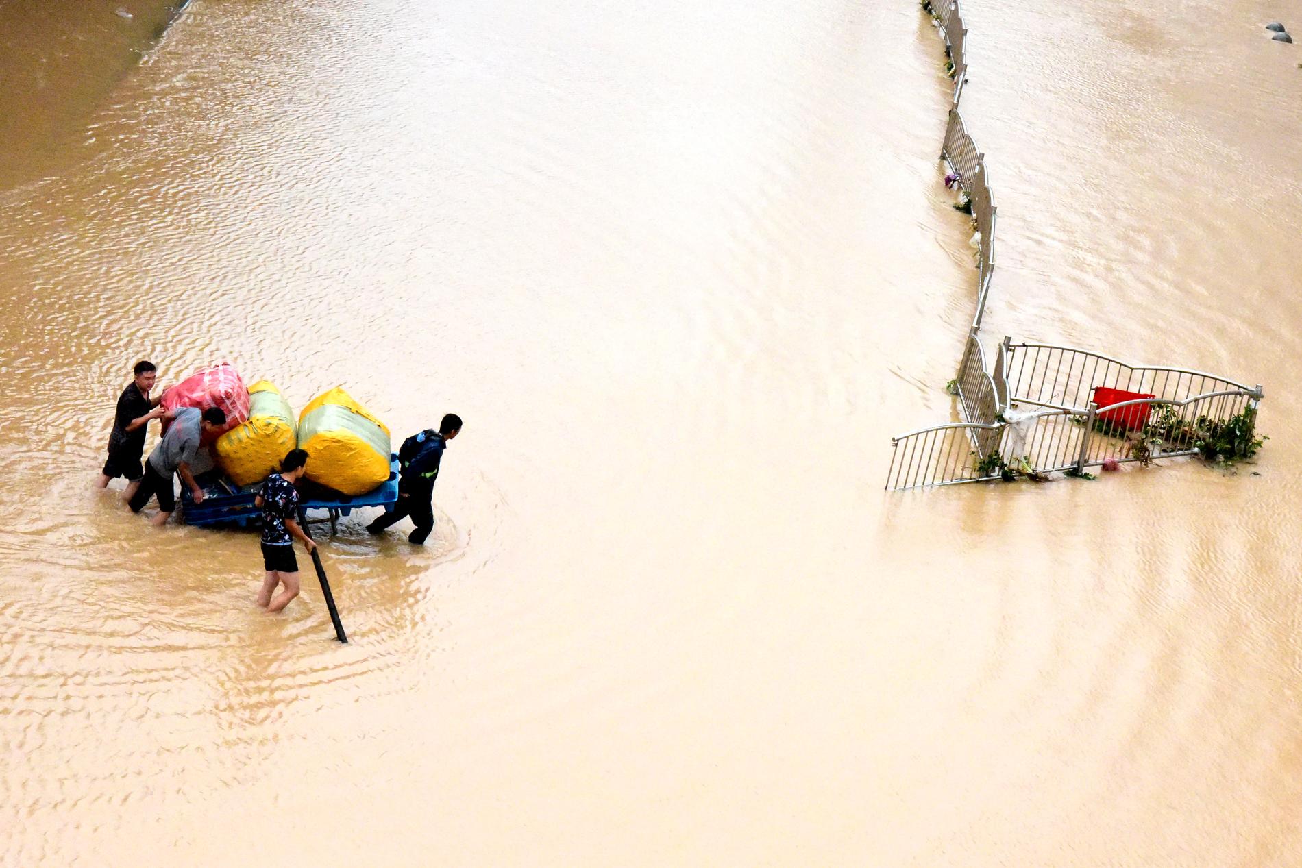 Zhengzhoubor förflyttar sina ägodelar längs med en översvämmad gata i staden.