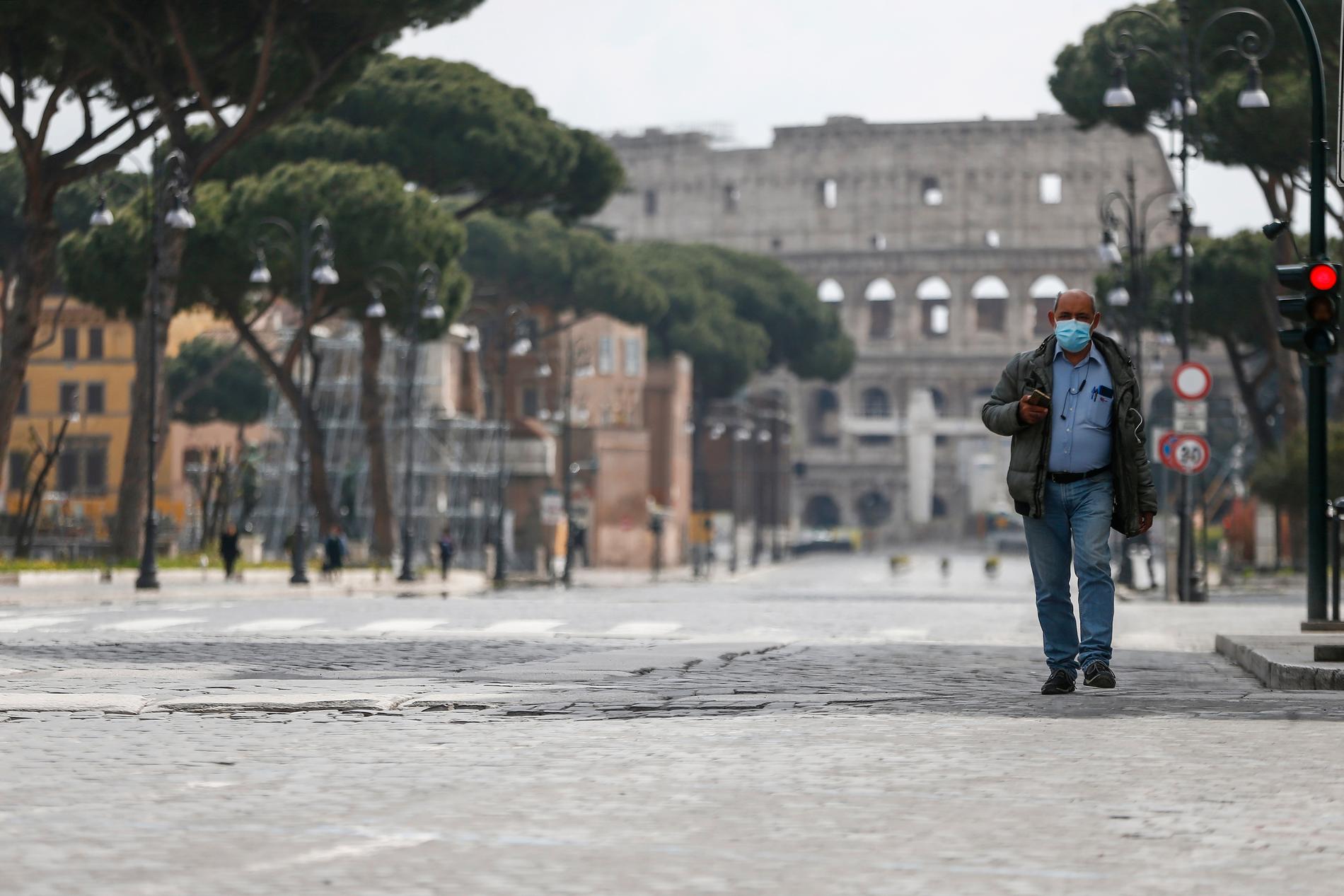 En man går längs en folktom gata i Rom. I bakgrunden skymtar Colosseum.