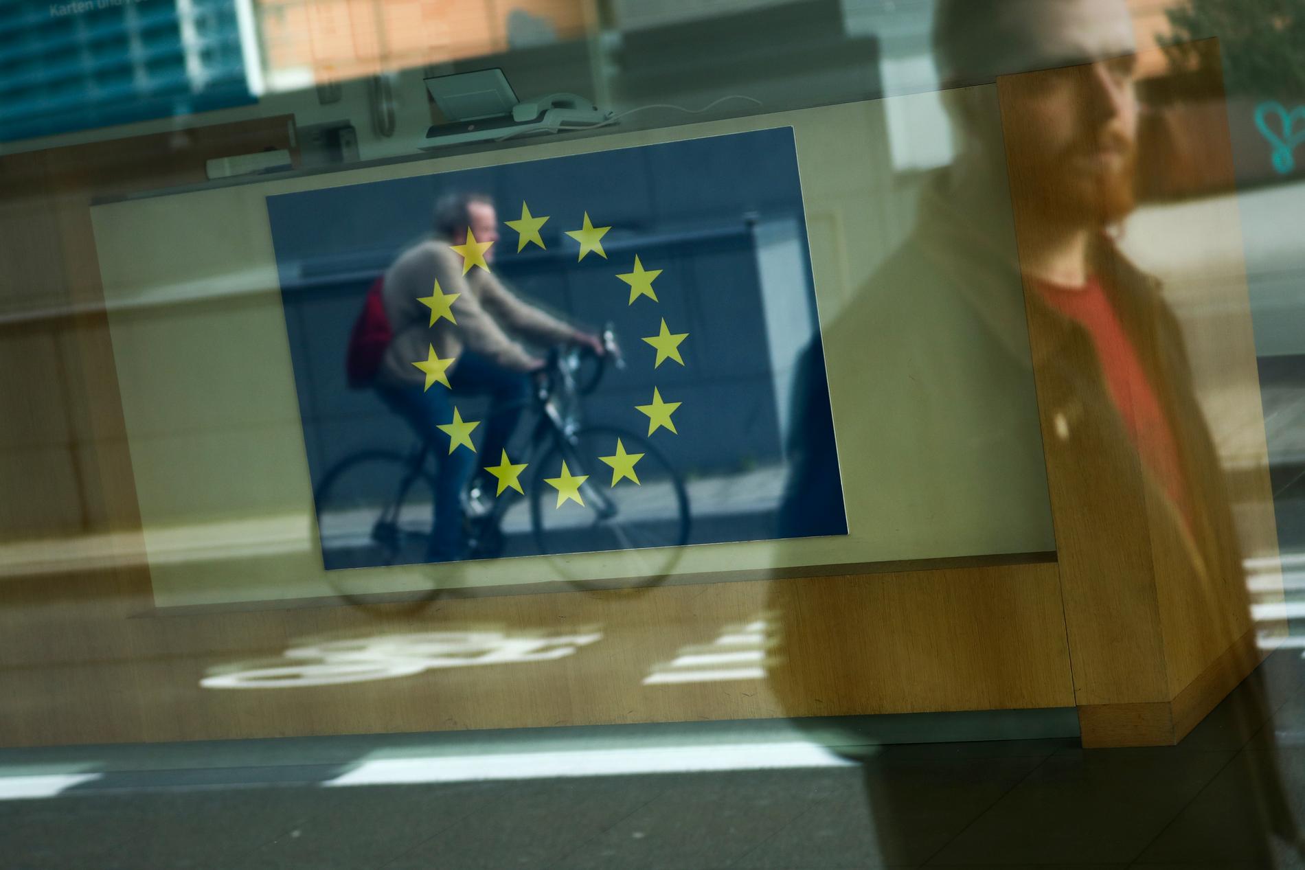 Förbipasserande speglas i ett fönster vid EU-kommissionens högkvarter i Bryssel.