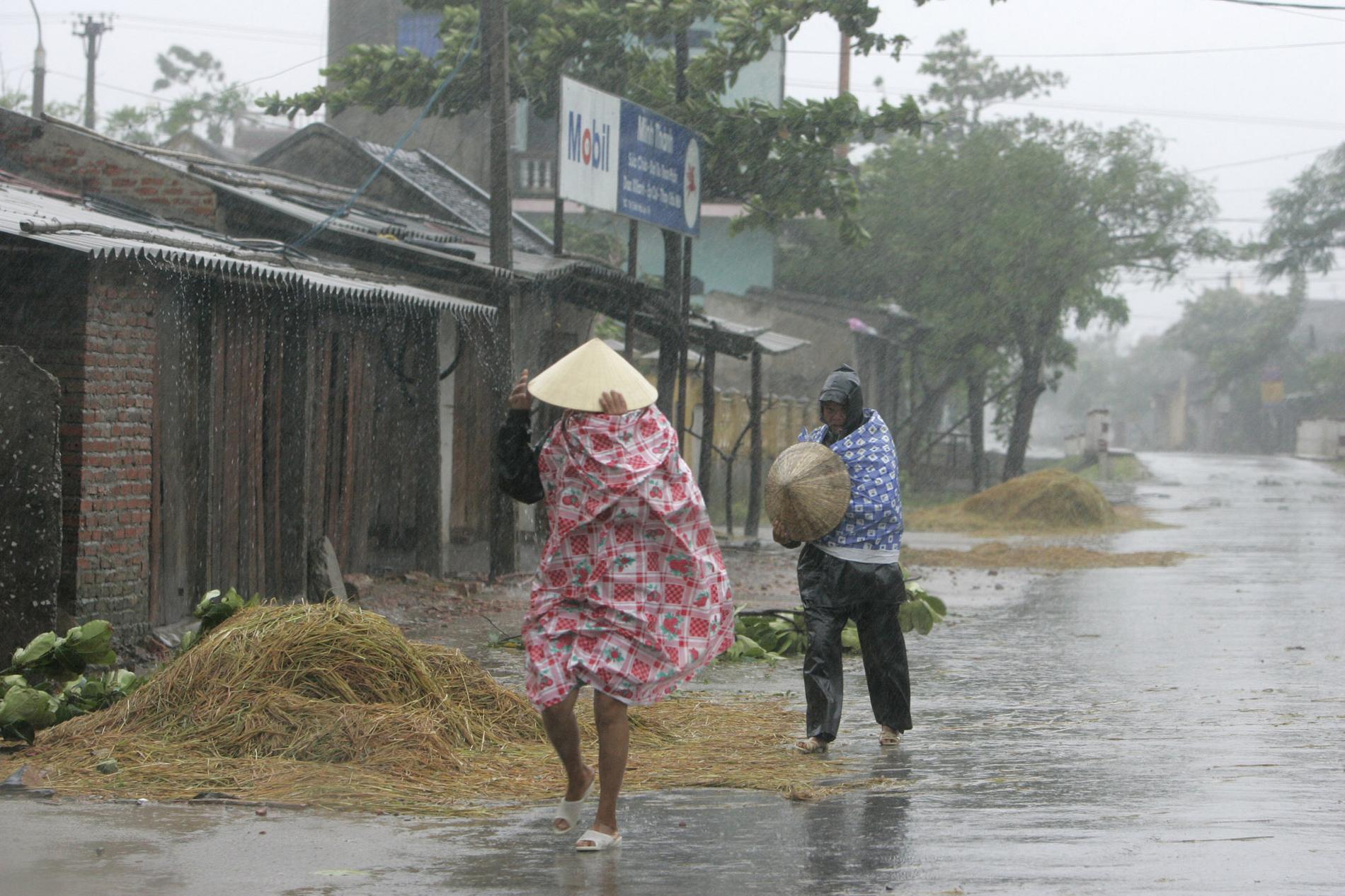 Två kvinnor promenerar i kraftigt regn under en tidigare storm i Vietnam. Arkivbild.