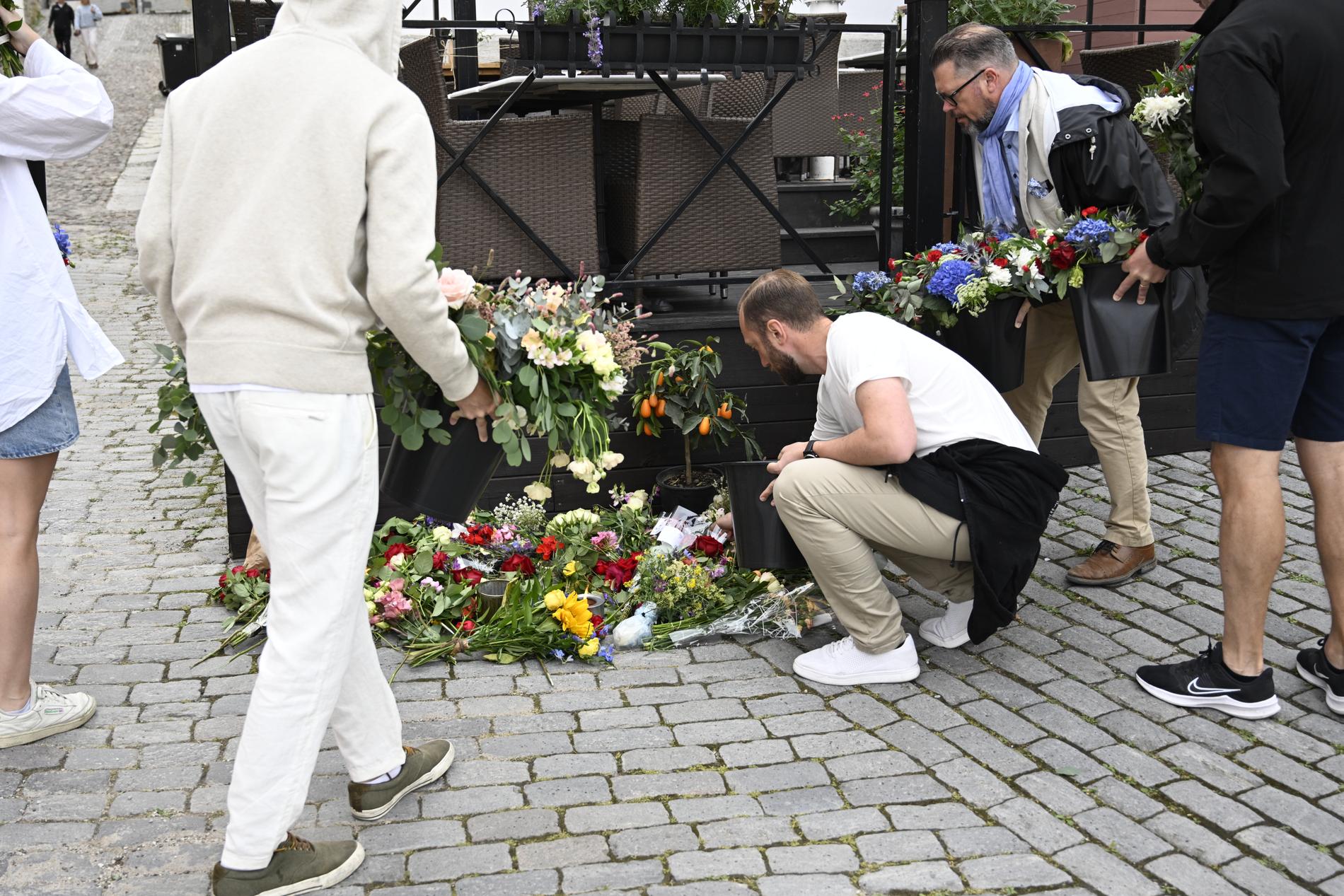 Flera människor lägger blommor på platsen där Ing-Marie mördades