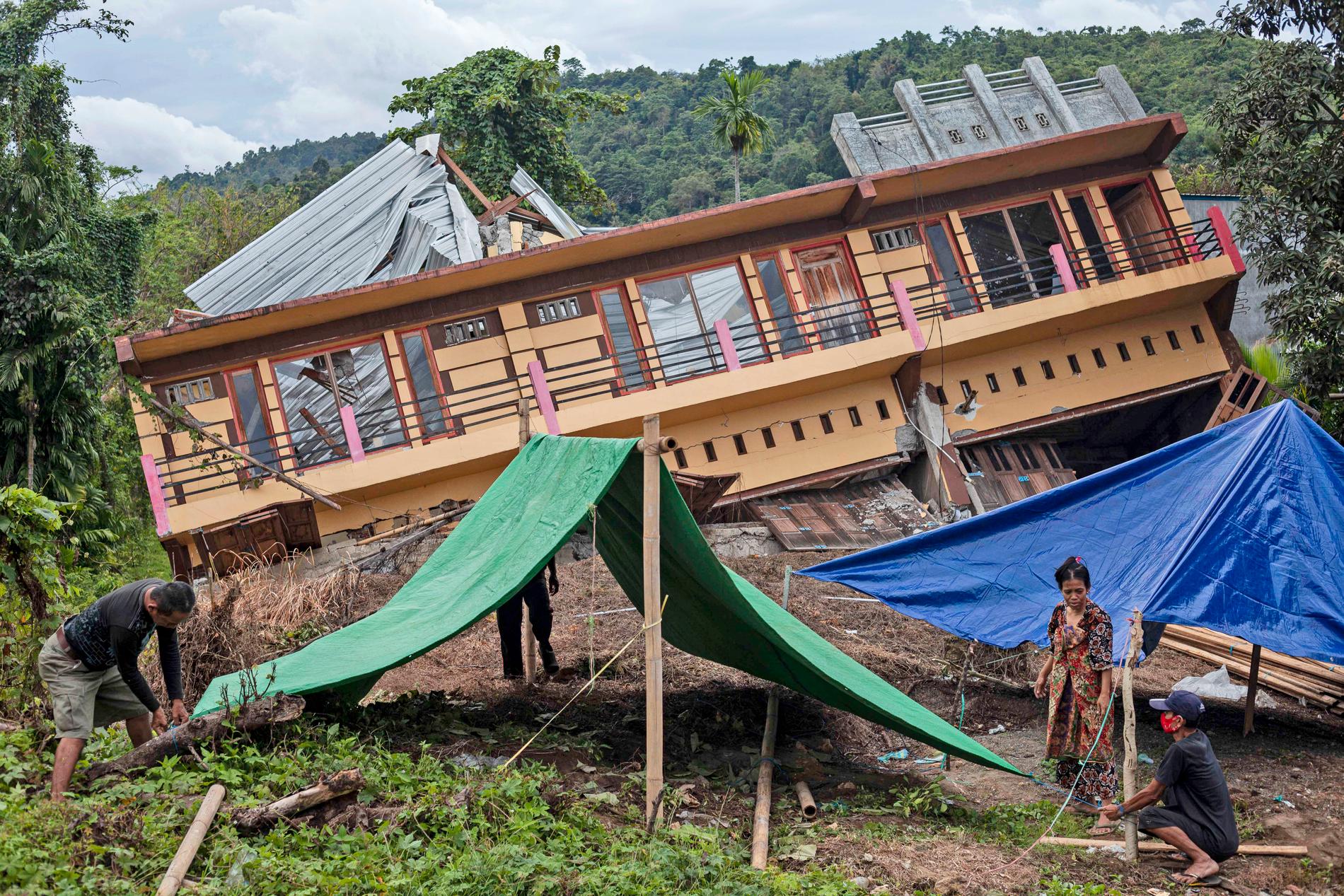 Invånare i Mamuju som förlorat sina hem i skalvet sätter upp provisoriska tält.