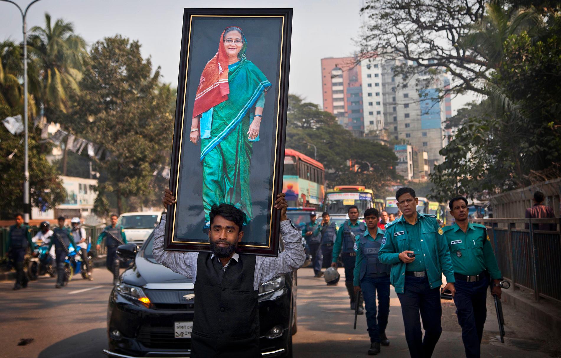 En anhängare av Awamiförbundet bär ett stort fotografi av premiärminister Sheikh Hasina under ett valmöte i Dhaka.
