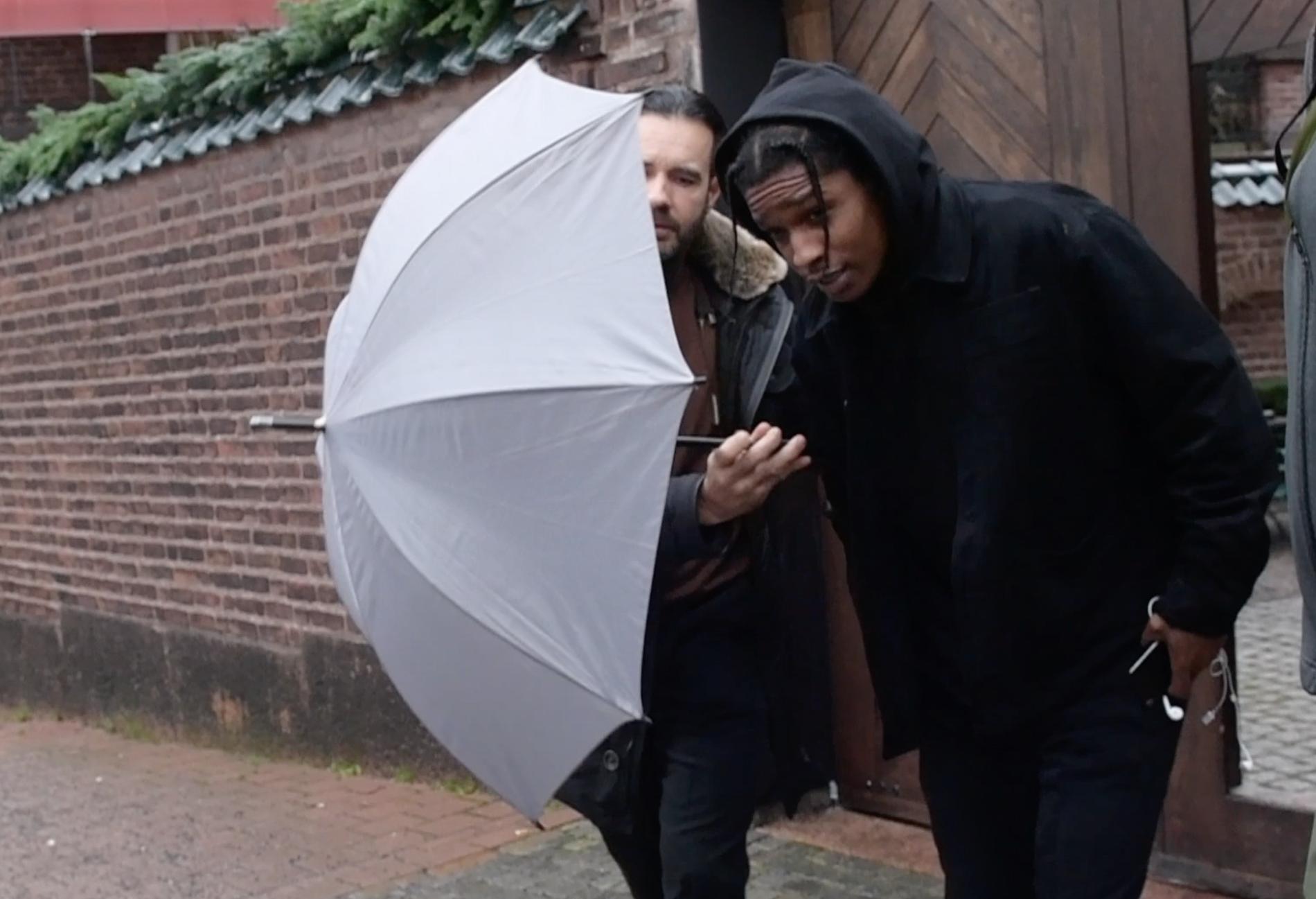 Asap Rocky är tillbaka i Stockholm vid lunchtid lämnade han lyxhotellet – skyddad av paraplyer.