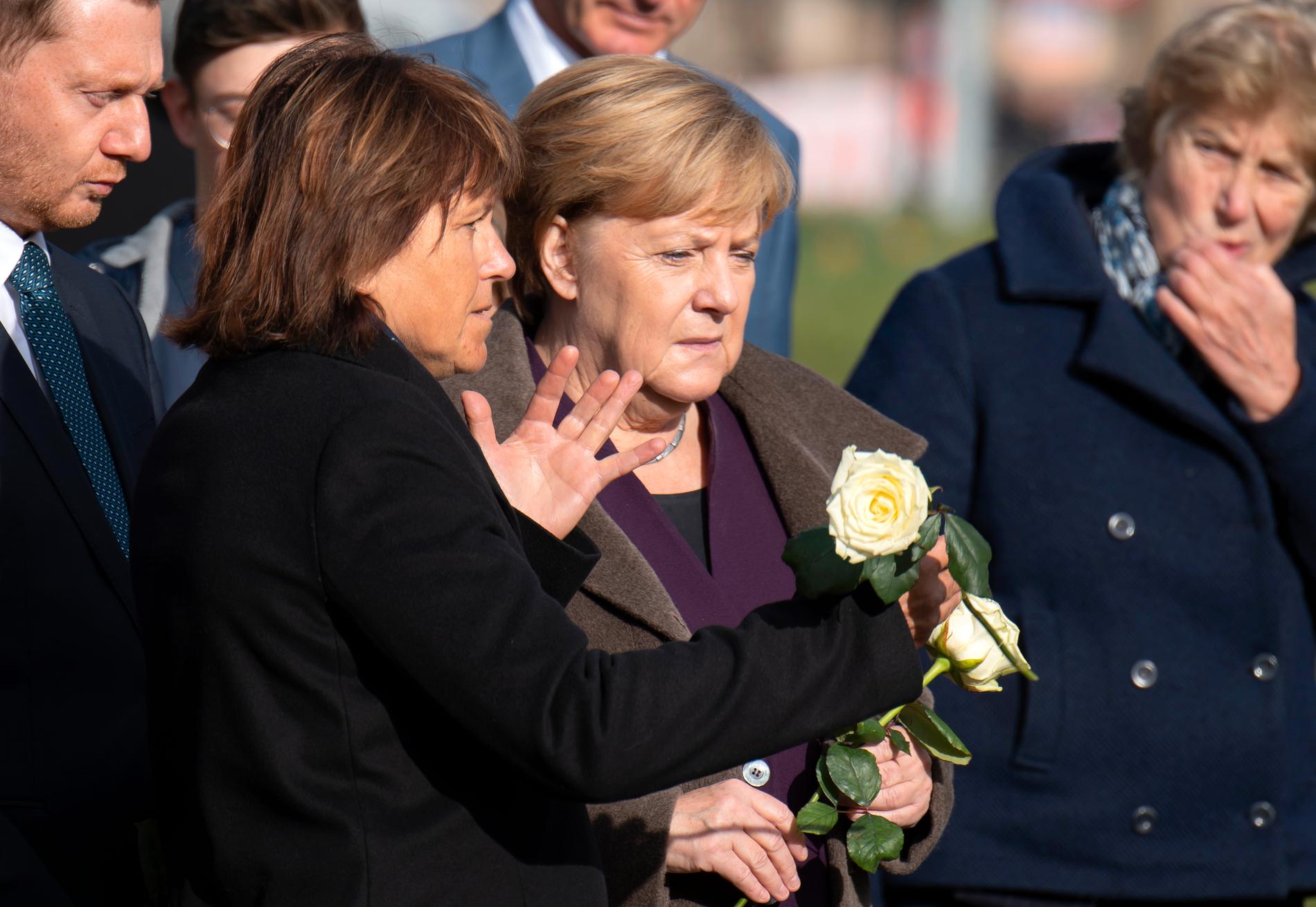 Angela Merkel (mitten) lade ned blommor på minnesplatsen i Zwickau för att hedra offren. På bilden syns också Zwickaus borgmästare Findeiss (vänster om Merkel) och Sachsens regionala regeringschef Michael Kretschmer i vänstra hörnet.