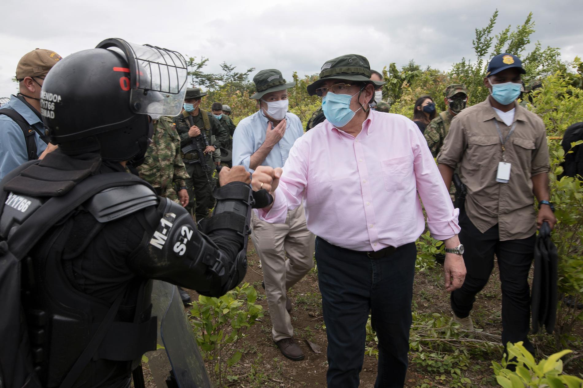 Colombias försvarsminister Carlos Holmes Trujillo, här i rosa skjorta, har avlidit efter att ha insjuknat i covid-19. Här träffar han poliser vid en insats mot en kokainodling i landet, den 30 december. Arkivbild.
