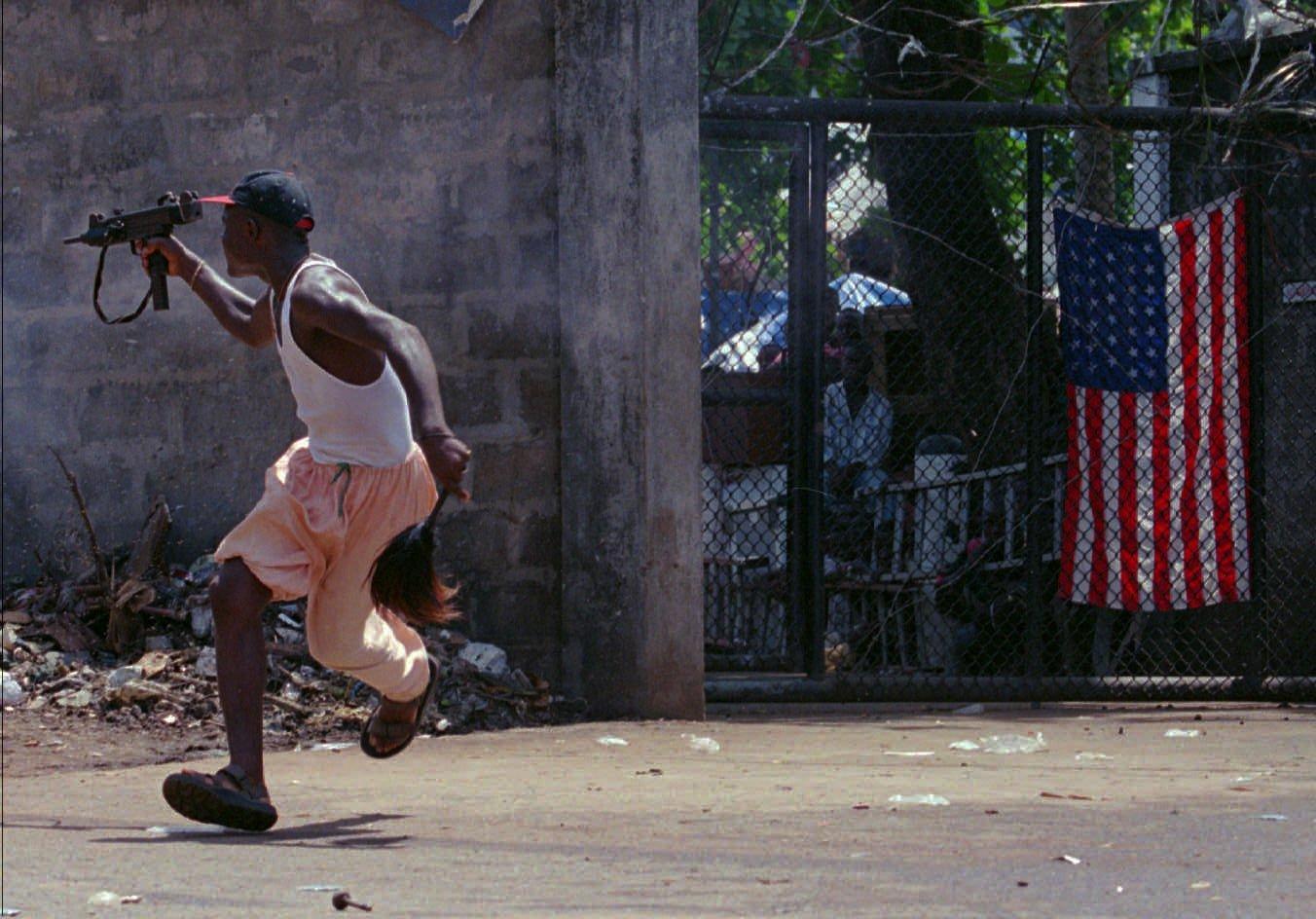 En rebell i Ulimo-gerillan i Liberia skjuter mot sina motståndare utanför en amerikansk beskickningsbyggnad 1996.