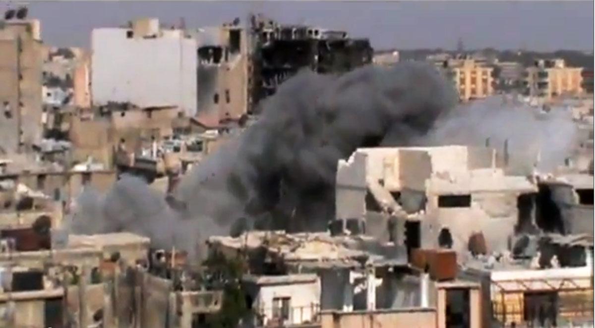 Rökmoln över staden Homs efter en regeringsstyrd bombattack.
