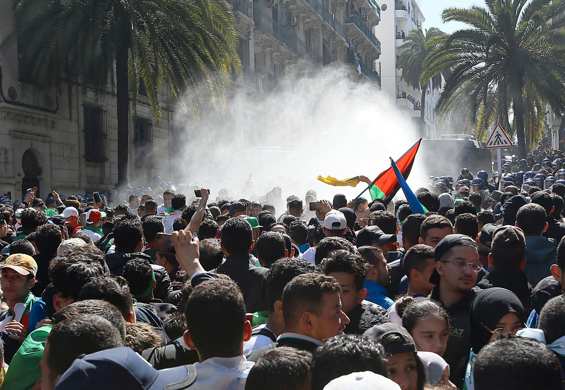 Polisen skjuter med vattenkanon mot demonstranter under fredagens massiva protester i Algeriets huvudstad Alger.