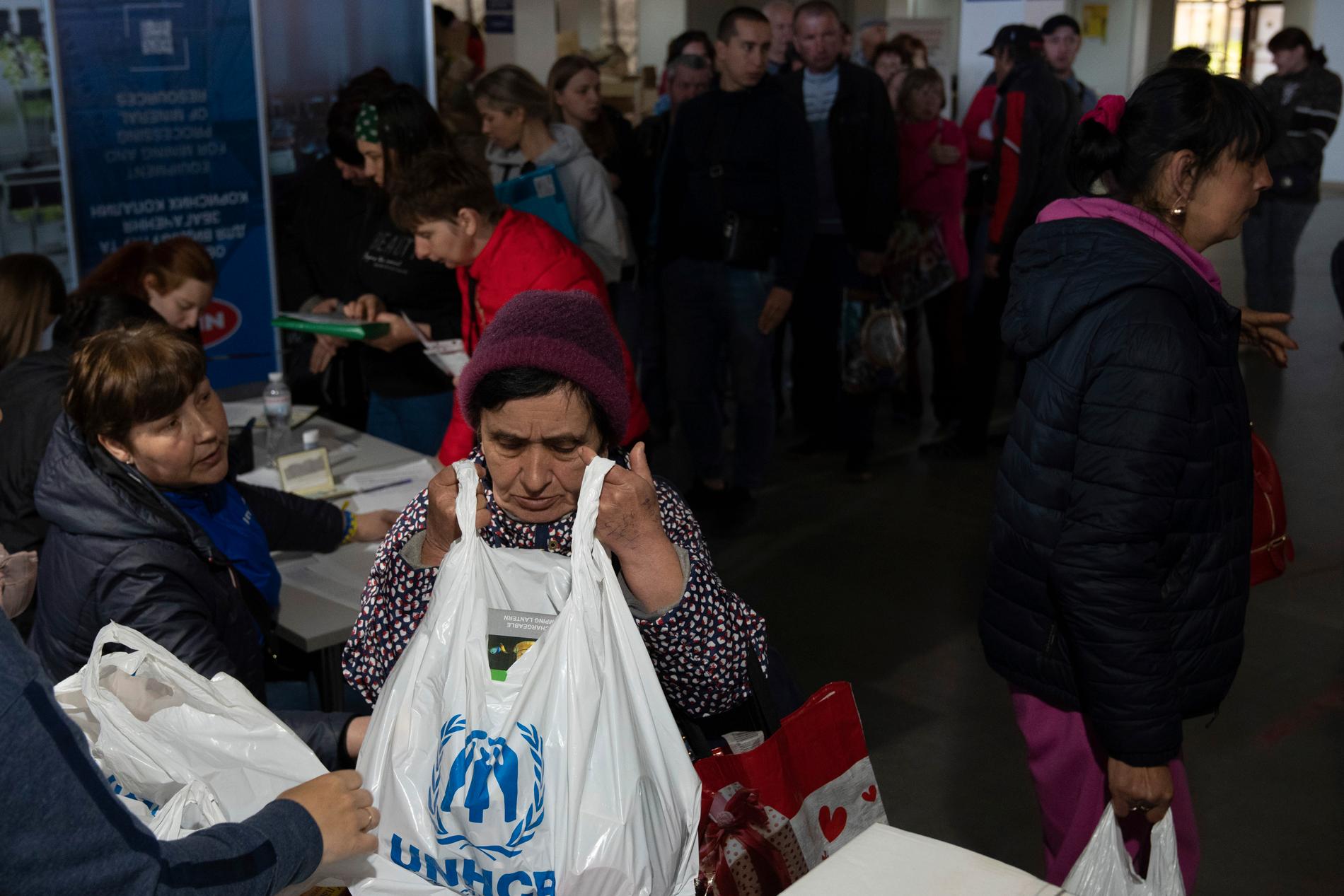 En kvinna får en påse från FN:s flyktingorgan UNHCR vid ett centrum i Zaporizjzja för människor som tvingats bort från sina hem på grund av kriget. Bilden togs i början av maj.