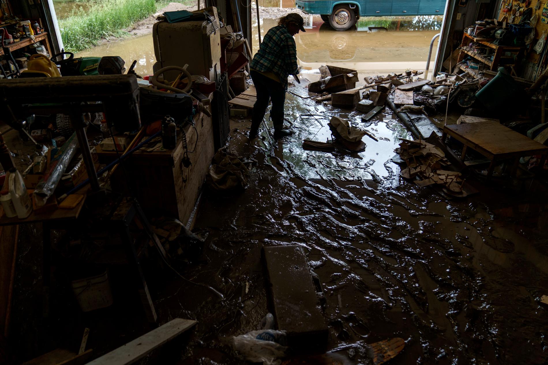 En kvinna går genom leran i föräldrahemmet som blev förstörd av vattenmassorna. 
