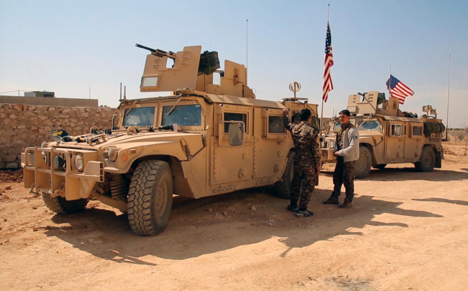 Medlemmar i milisen SDF vid amerikanska stridsfordon i norra Syrien. Arkivbild.