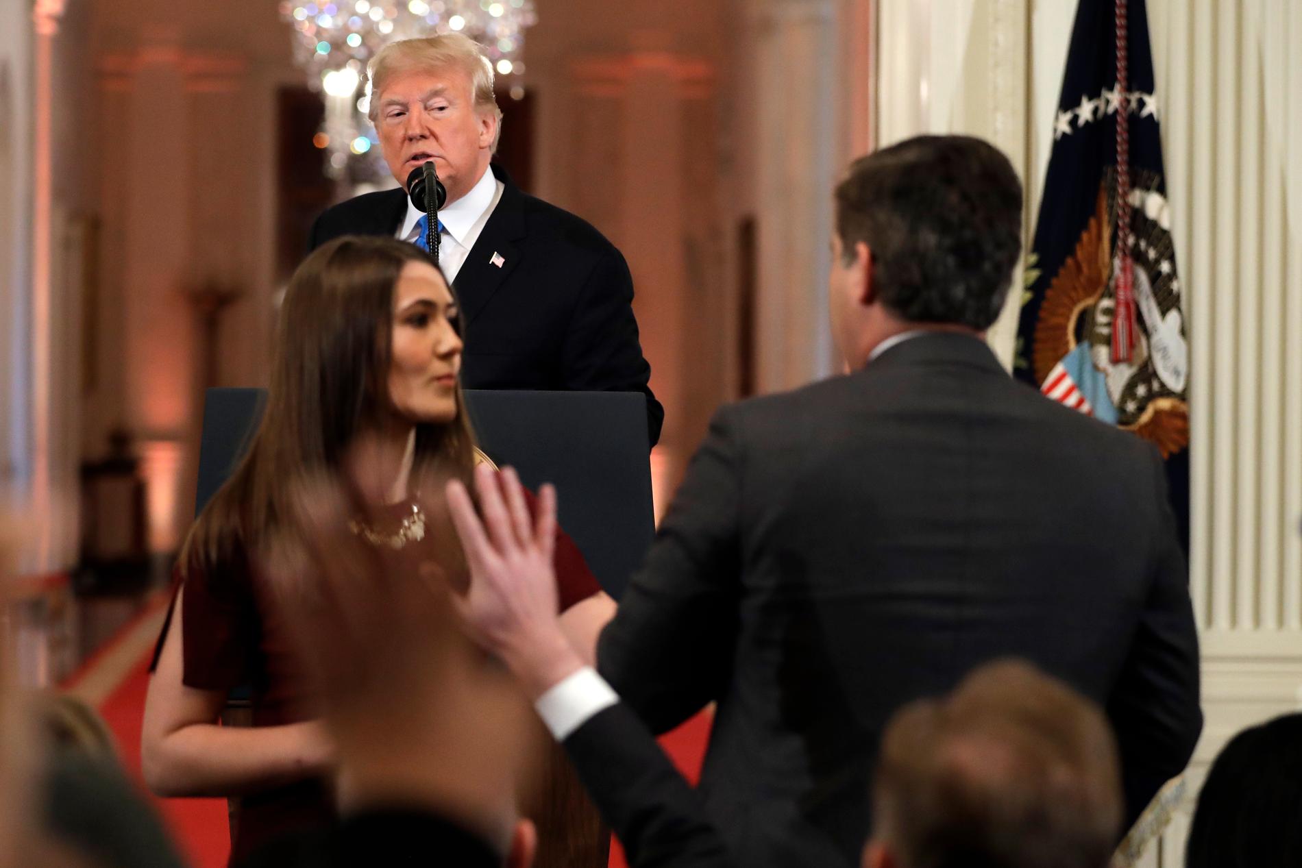 President Donald Trump ser på när en praktikant försöker ta mikrofonen från CNN-journalisten Jim Acosta under pressträffen i Vita huset den 7 november.