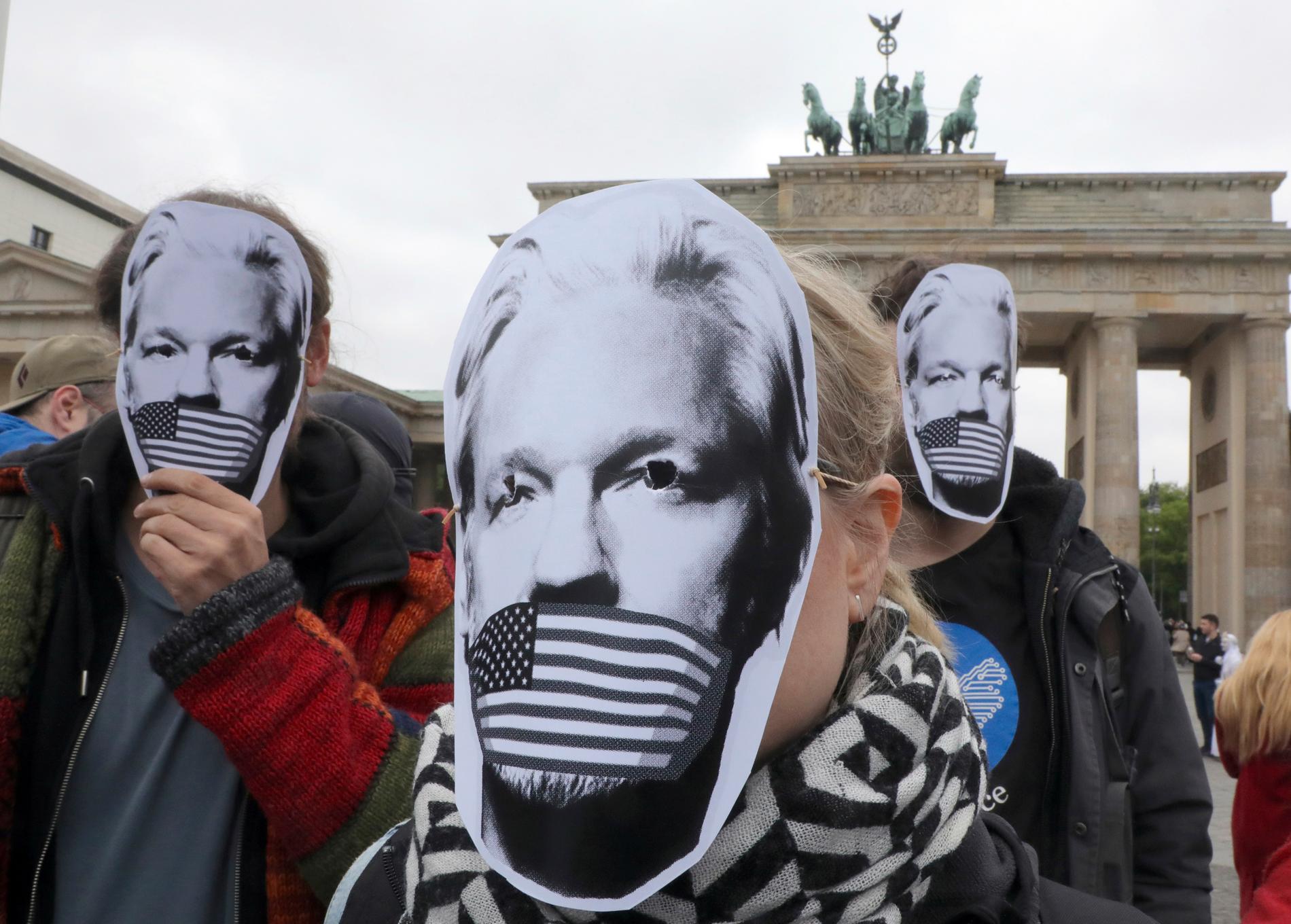 Personer i Tyskland bär pappersmasker för att protestera för eventuell utlämning av Julian Assange till USA.