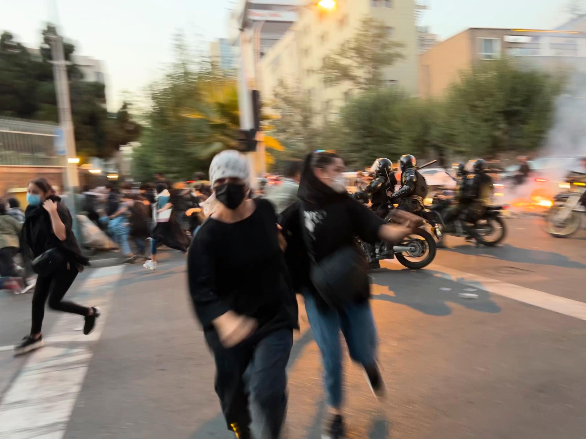 Demonstranter springer från säkerhetsstyrkor under protest i Teheran, måndag 19 september.