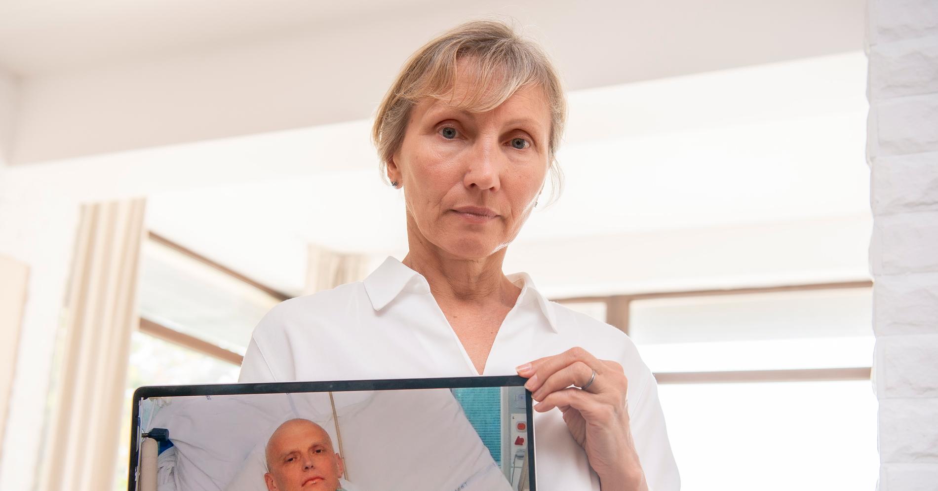 Marina håller upp en bild, som uppmärksammats världen över, på sin döda make  Aleksandr ”Sasha” Litvinenko i en sjuksäng.