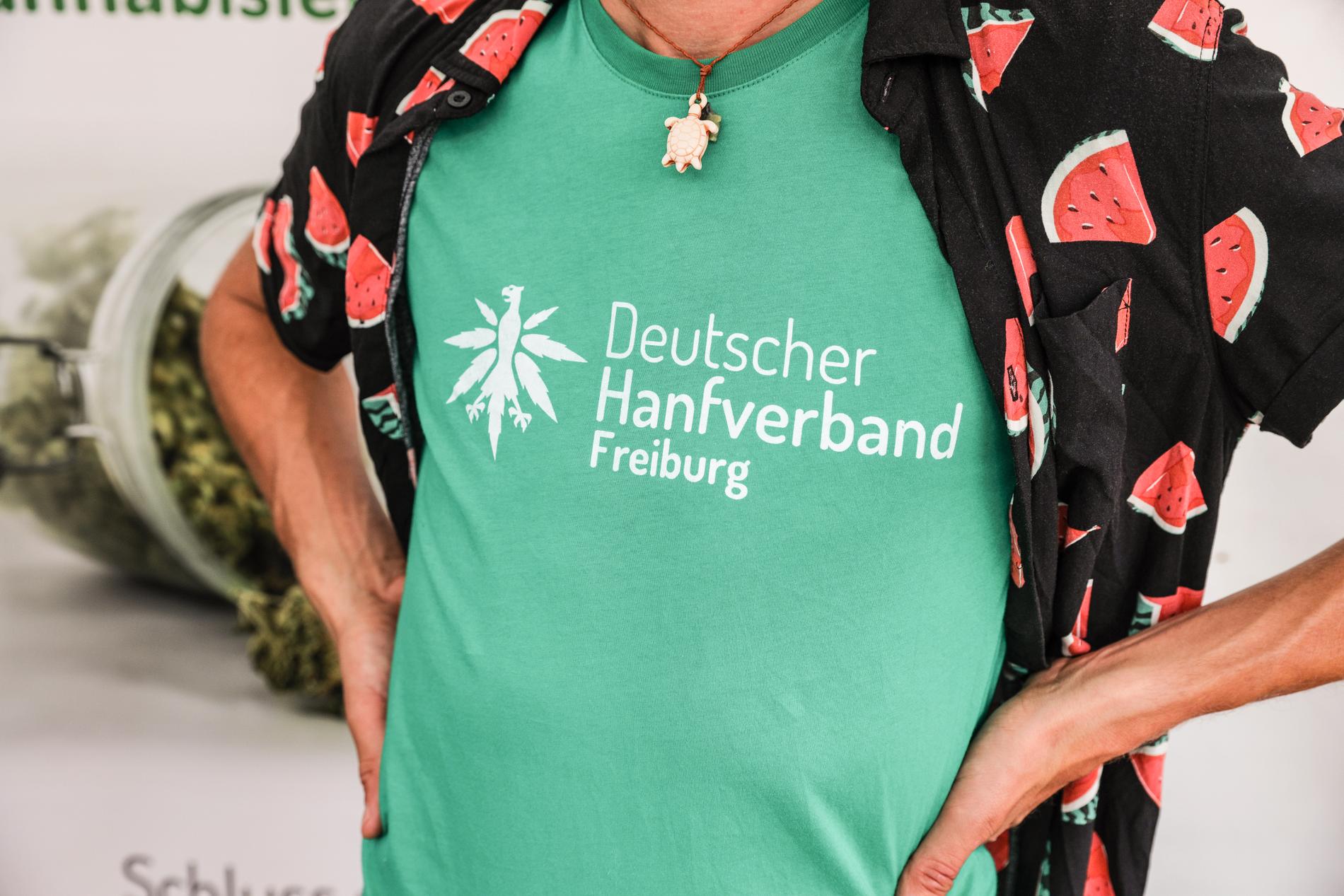 En medlem av Deutscher Hanfverband (Tyska hampförbundet) står vid en infomonter i den årliga hampaparaden den 12 augusti 2023 i Berlin.
