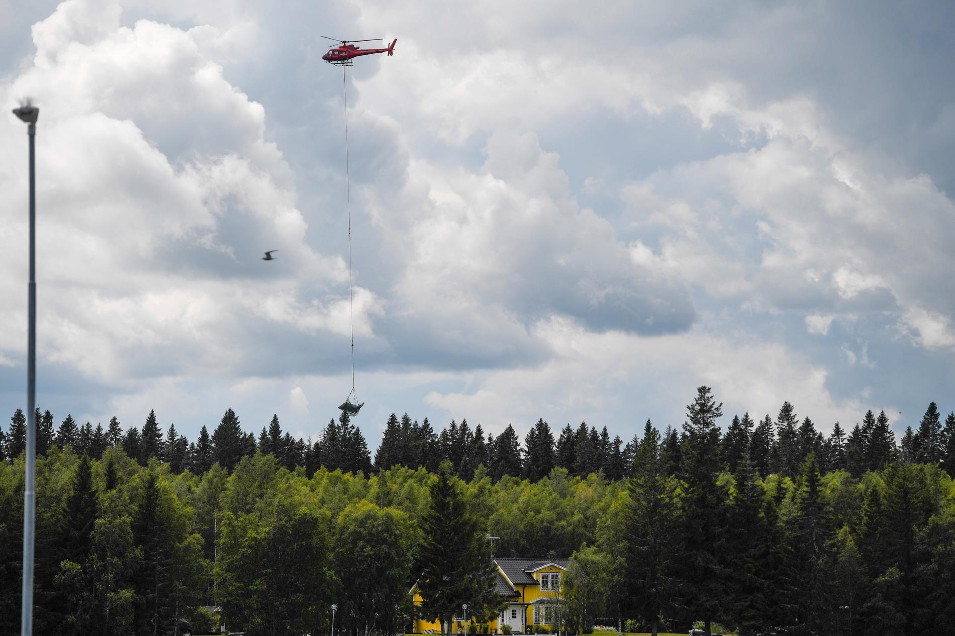 En helikopter bärgar vrakdelar från flygplanet efter olyckan i Umeå 14 juli 2019. Arkivbild.