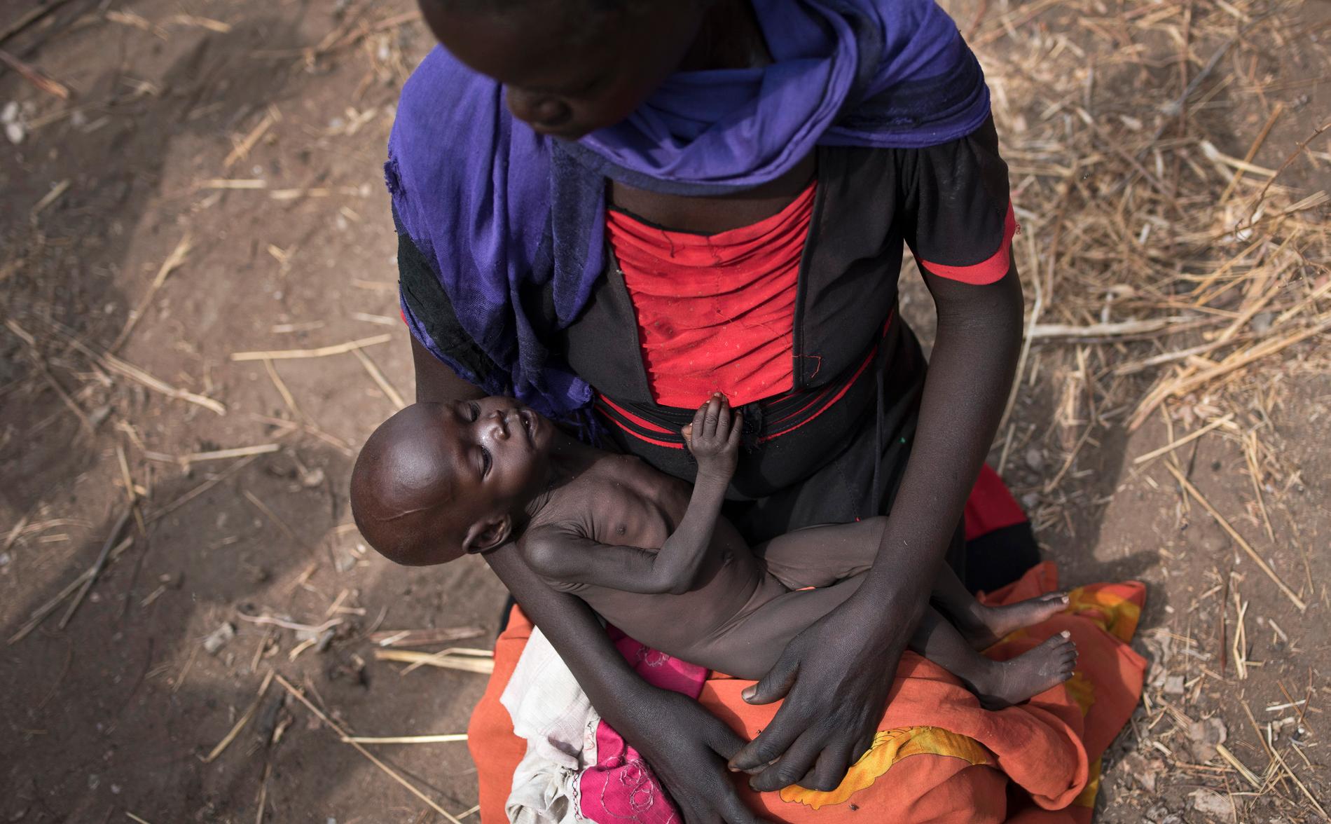 Adel Bol, 20 år, vaggar sin tio månaders gamla dotter Akir Mayen vid matutdelning i Malualkuel i Sydsudan under fjolårets hungersnöd. Arkivbild.