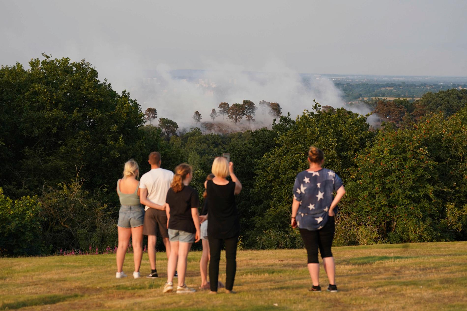 Människor tittar på en stor skogsbrand i skogsmark i Lickey Hills Country Park i utkanten av Birmingham, England. Ett sextiotal brandmän tar itu med branden som bröt ut vid parken tidigare idag.