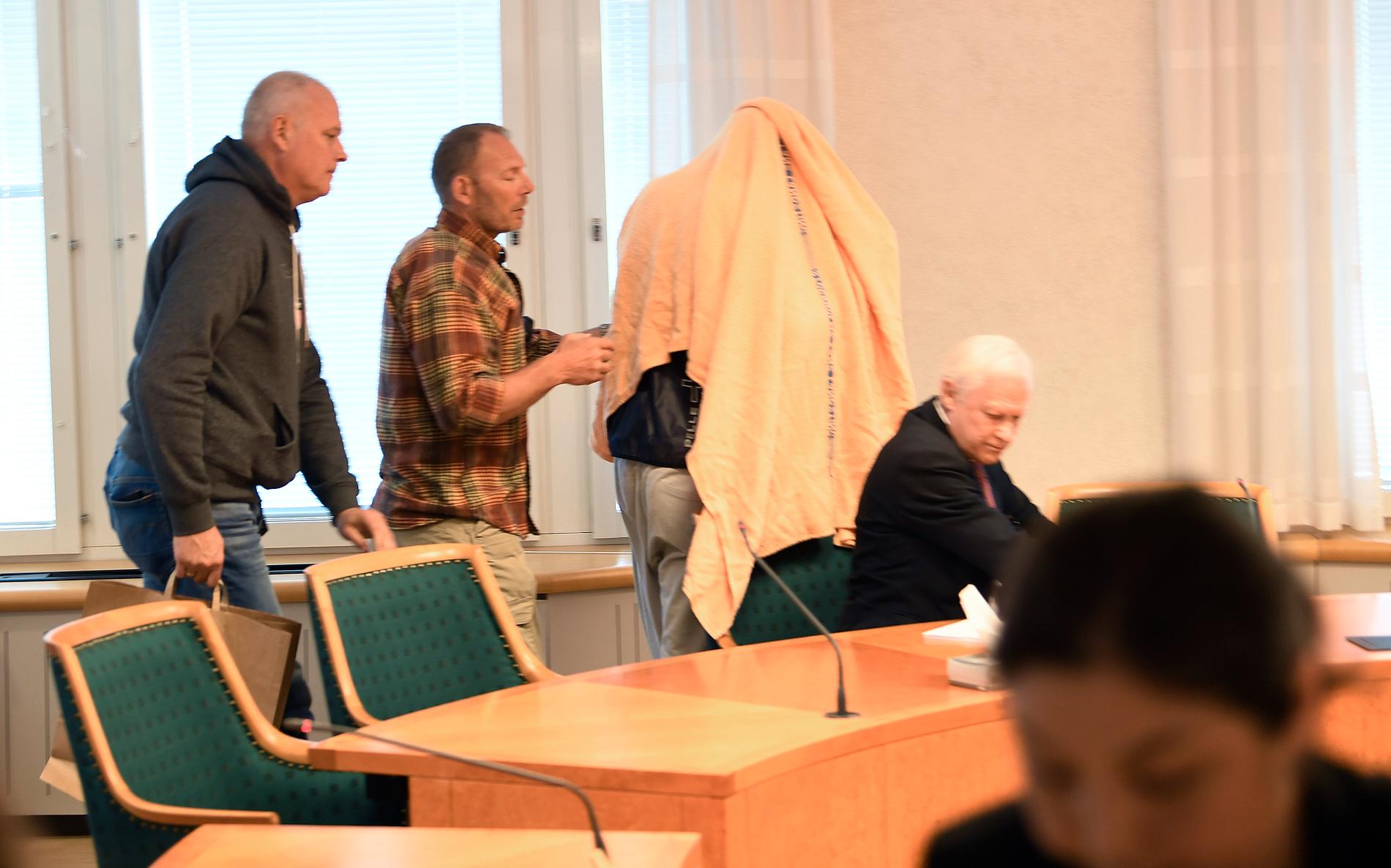 Den tidigare Tre Kronor-spelade var täckt av en filt när han fördes in till häktingsförhandlingen. 