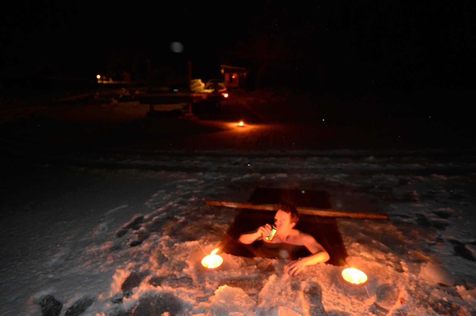 Johannes tar ett dopp i isvaken som mågen Simon sågat upp utanför bastun. Foto: LASSE ALLARD