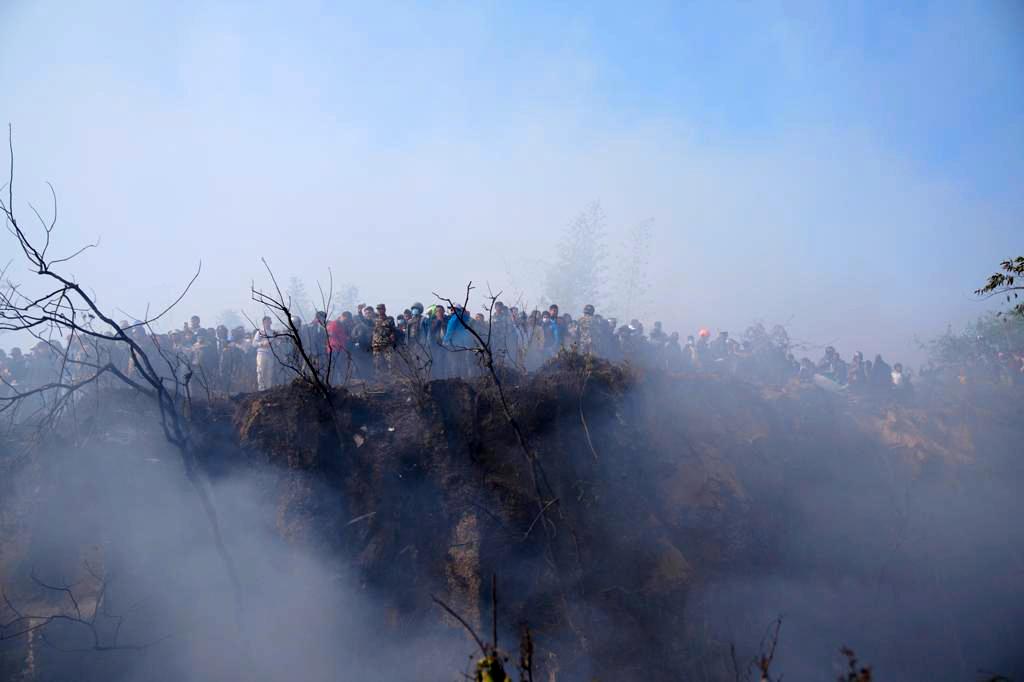  Lokalinvånare tittar ner på det rykande flygplansvraket i ravinen i Pokhara.