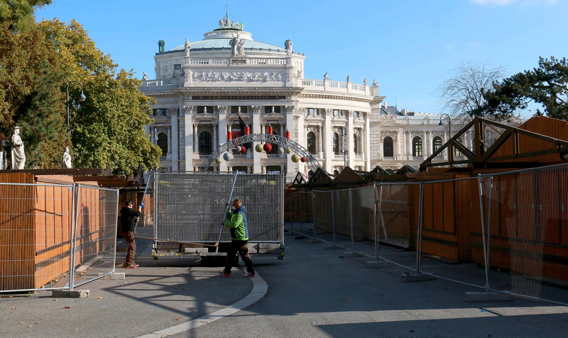 Arbetare bygger ett staket runt julmarknaden framför Burgtheater i Wien, vars öppning har skjutits upp på obestämd framtid.