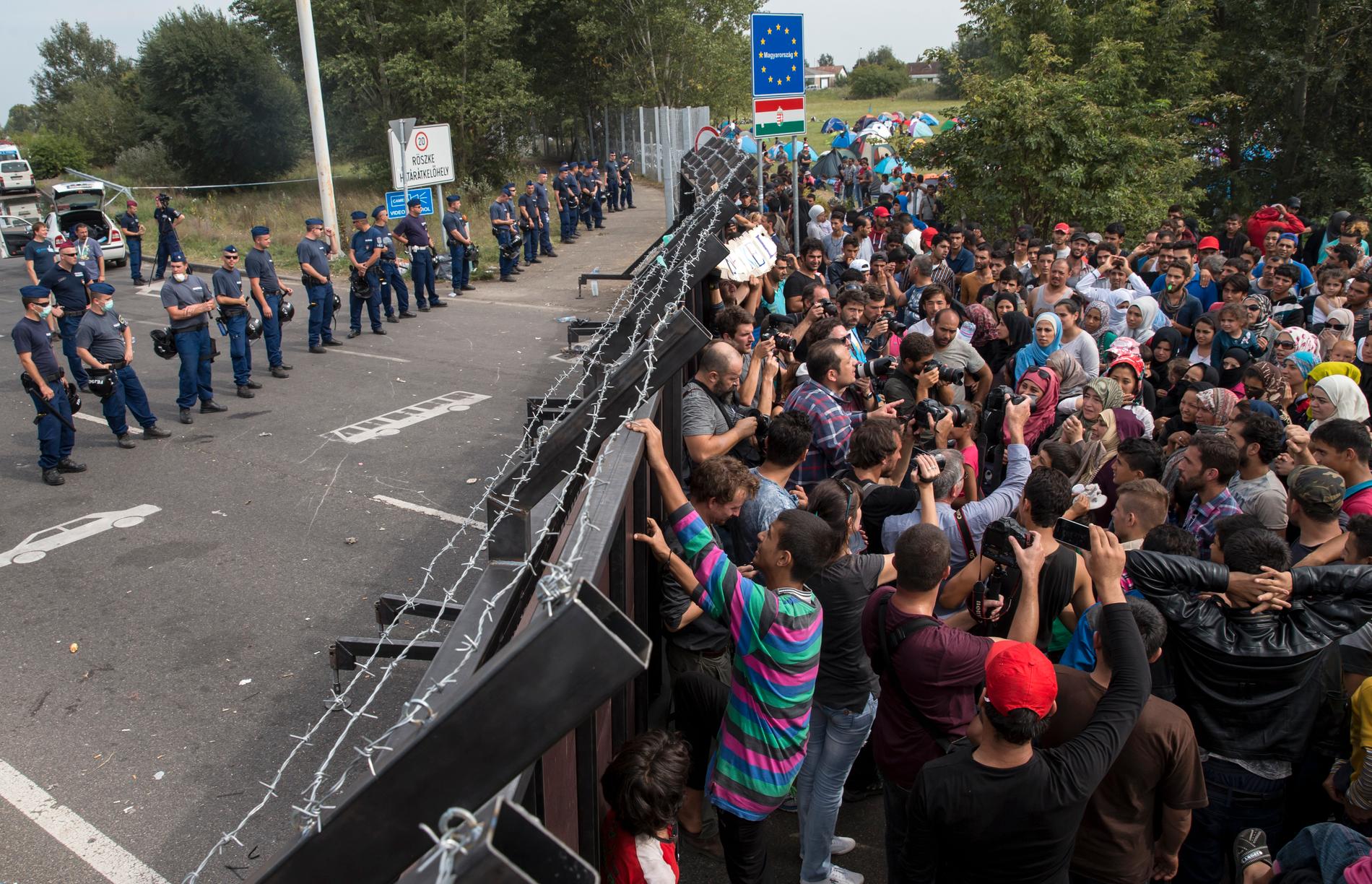 Migranter framför barriären.