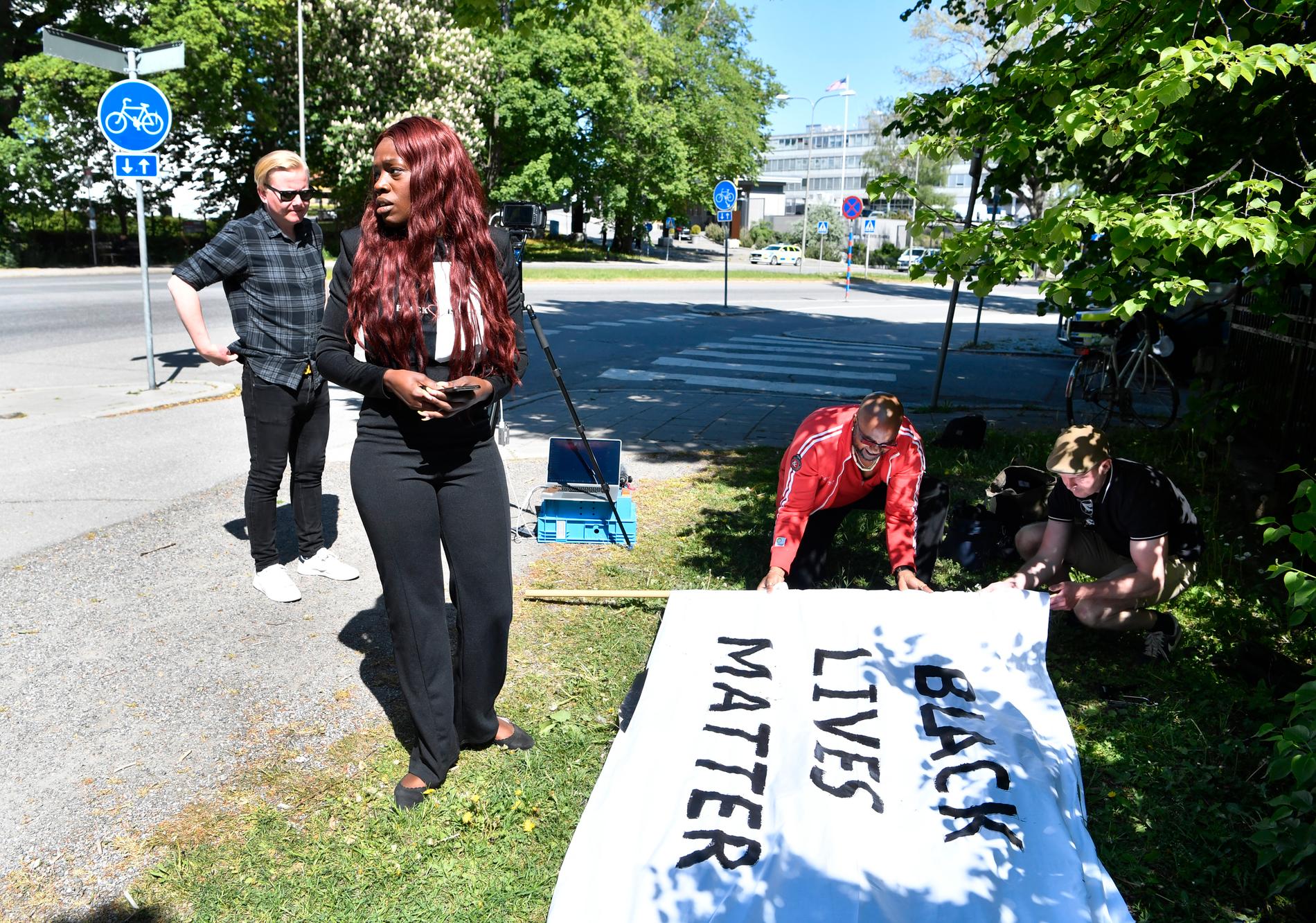 Aysha Jones, som är en av arrangörerna, deltar vid en manifestation utanför amerikanska ambassaden. Demonstrationen är digital och endast talarna är på plats vid ambassaden.