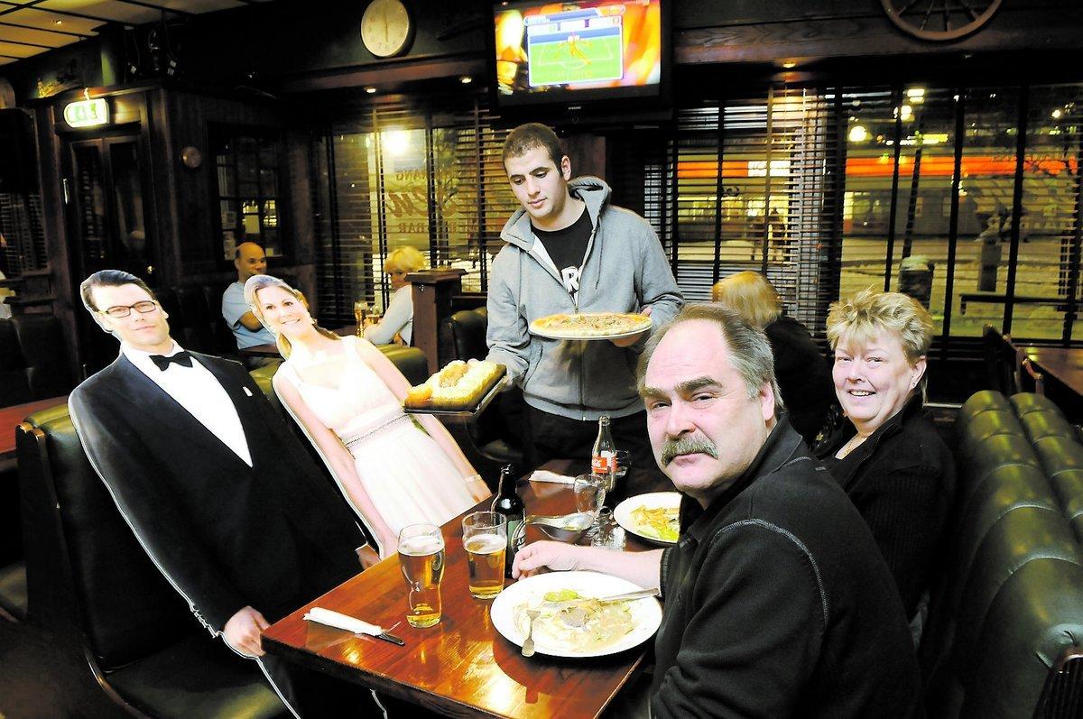 Paul Soume serverar en plankstek med pilsner till Daniel och en Vesuvio med cola till Victoria. Sällskapet Thomas Eriksson, 55, och Susanne Flaherty, 53, skålar glatt.