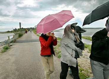 DRIPP DROPP Turisterna vände ryggar och paraplyer mot blåsten och regnet vid fyren Långe Erik på Ölands norra udde. Enligt uppgift borde solen skina här.