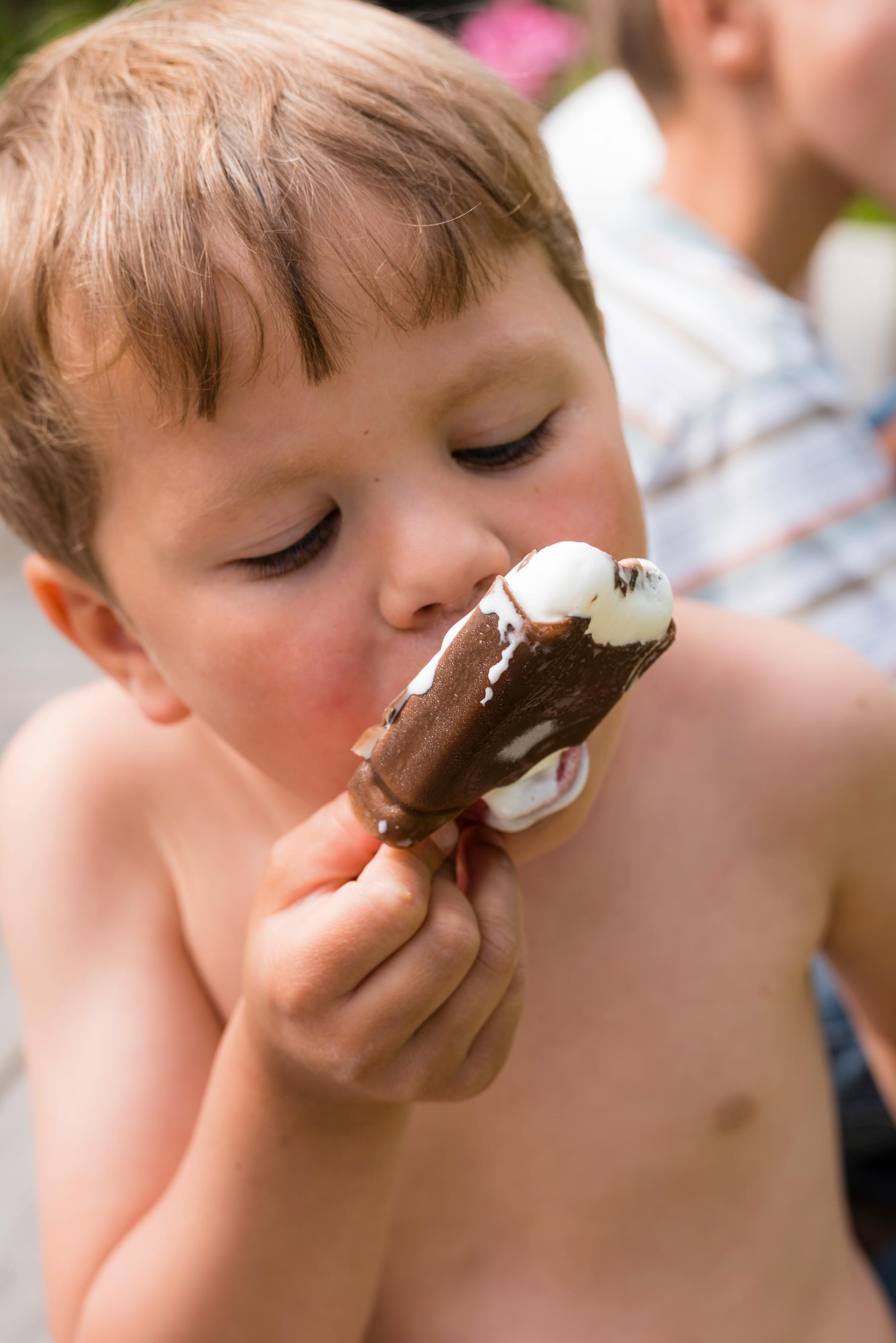 Ett barn äter glass i värmen på sommaren.