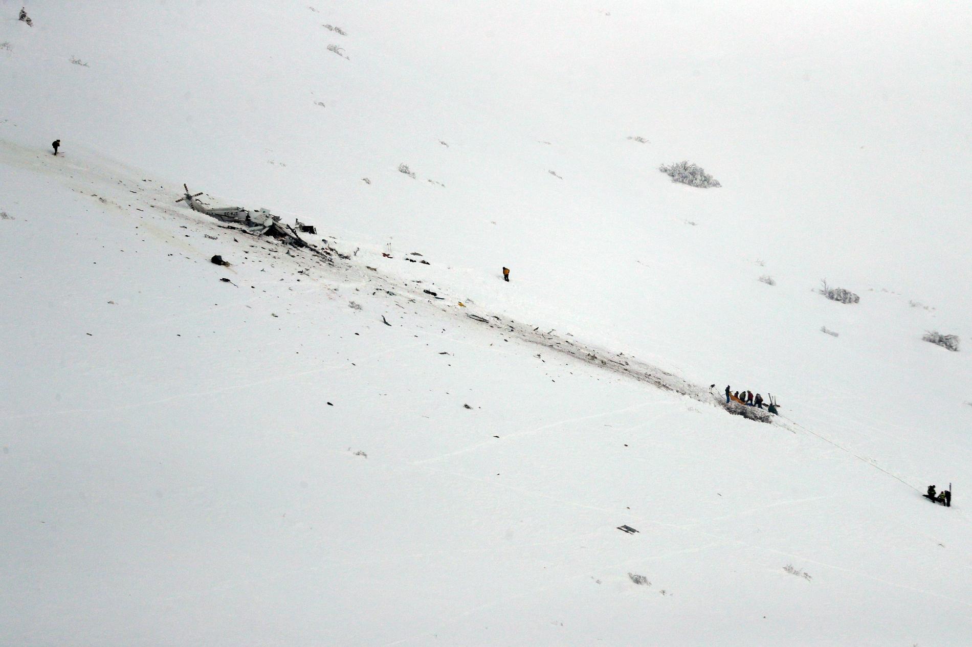 Räddningsarbetare kämpar sig upp mot den kraschade helikoptern.