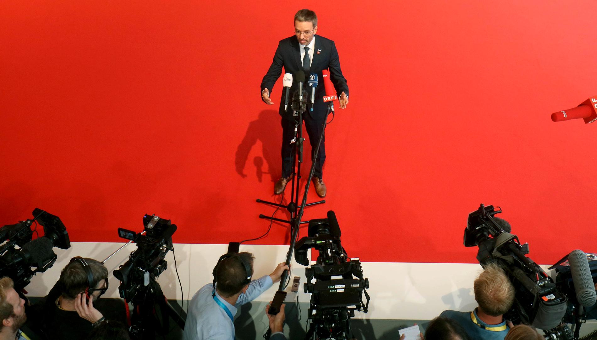 Österrikes inrikesminister Herbert Kickl framför mediernas kameror vid en tidigare presskonferens. Arkivbild.