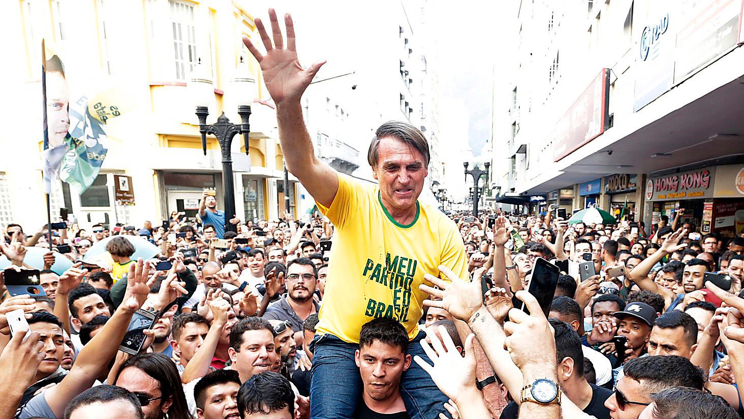 SEGERSÄKER Den högerextreme presidentkandidaten Jair Bolsonaro bärs fram av supportrar under presidentvalskampanjen. Strax efter att bilden togs knivhöggs han – en attack som stärkte hans position ytterligare.