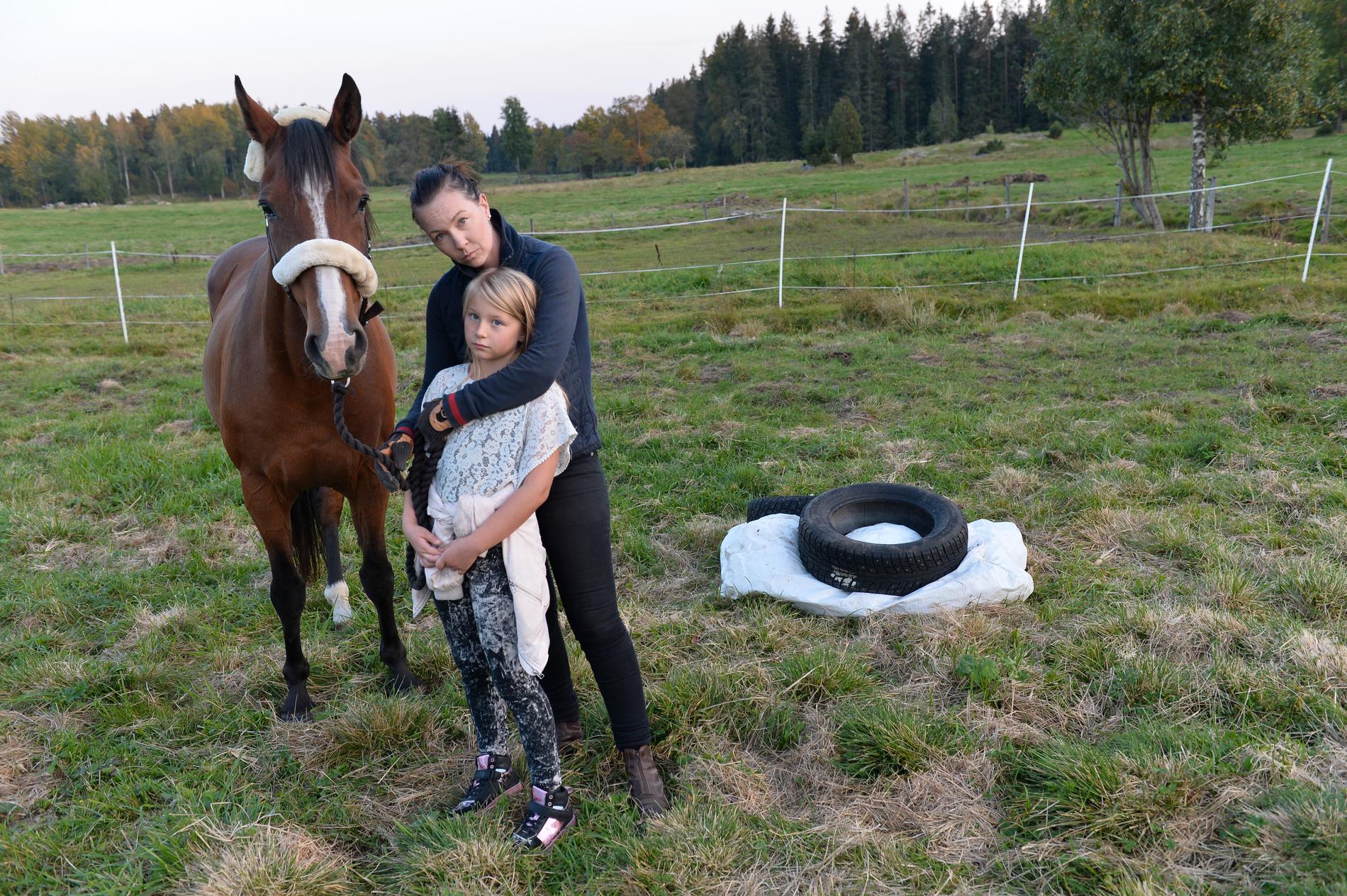 Åsa Karlsson och dottern Tess tillsammans med hästen Vicke på platsen där familjens ponny hittades död.