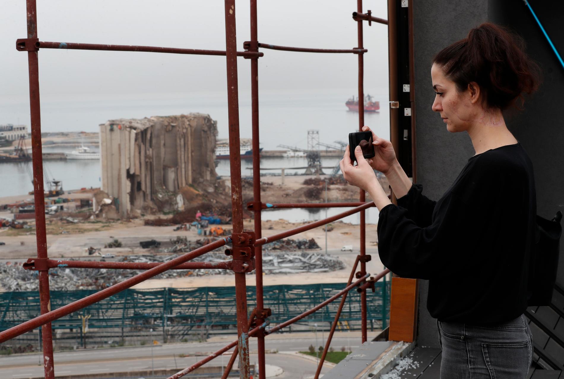 Joana Dagher, 33, som överlevde den våldsamma explosionen i Beirut förra året, tar en bild av hamnen ett halvår efter detonationen.