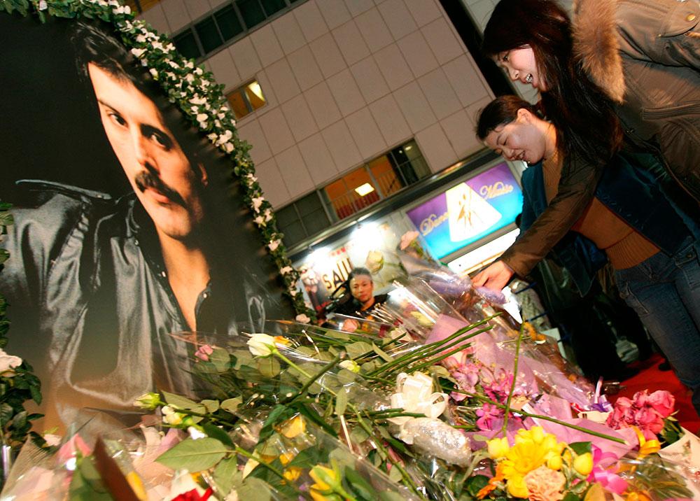 Queen-fans i Tokyo lämnar blommor vid Freddie Mercurys porträtt.