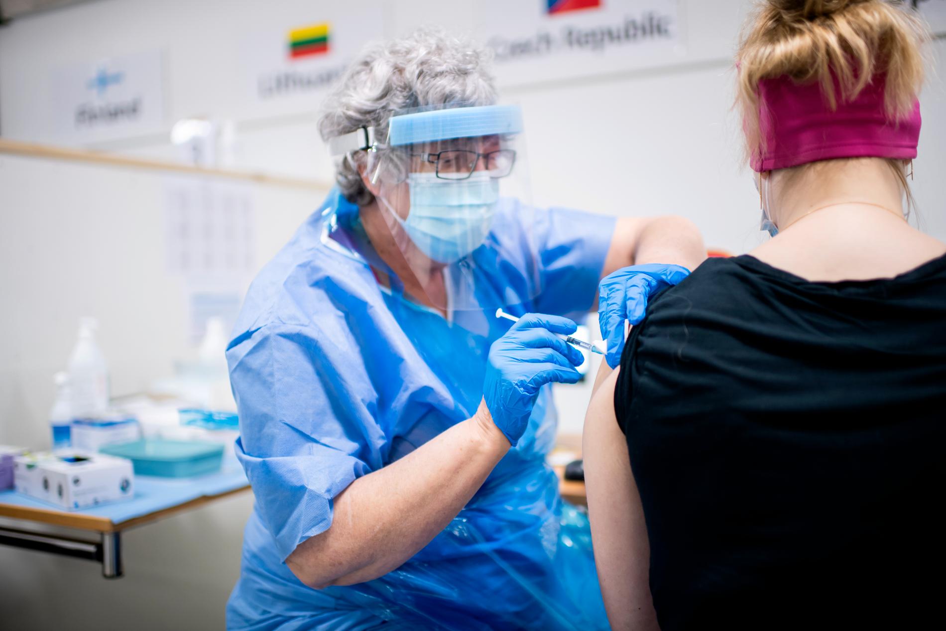En vaccinatör ger en kvinna en dos vaccin. 