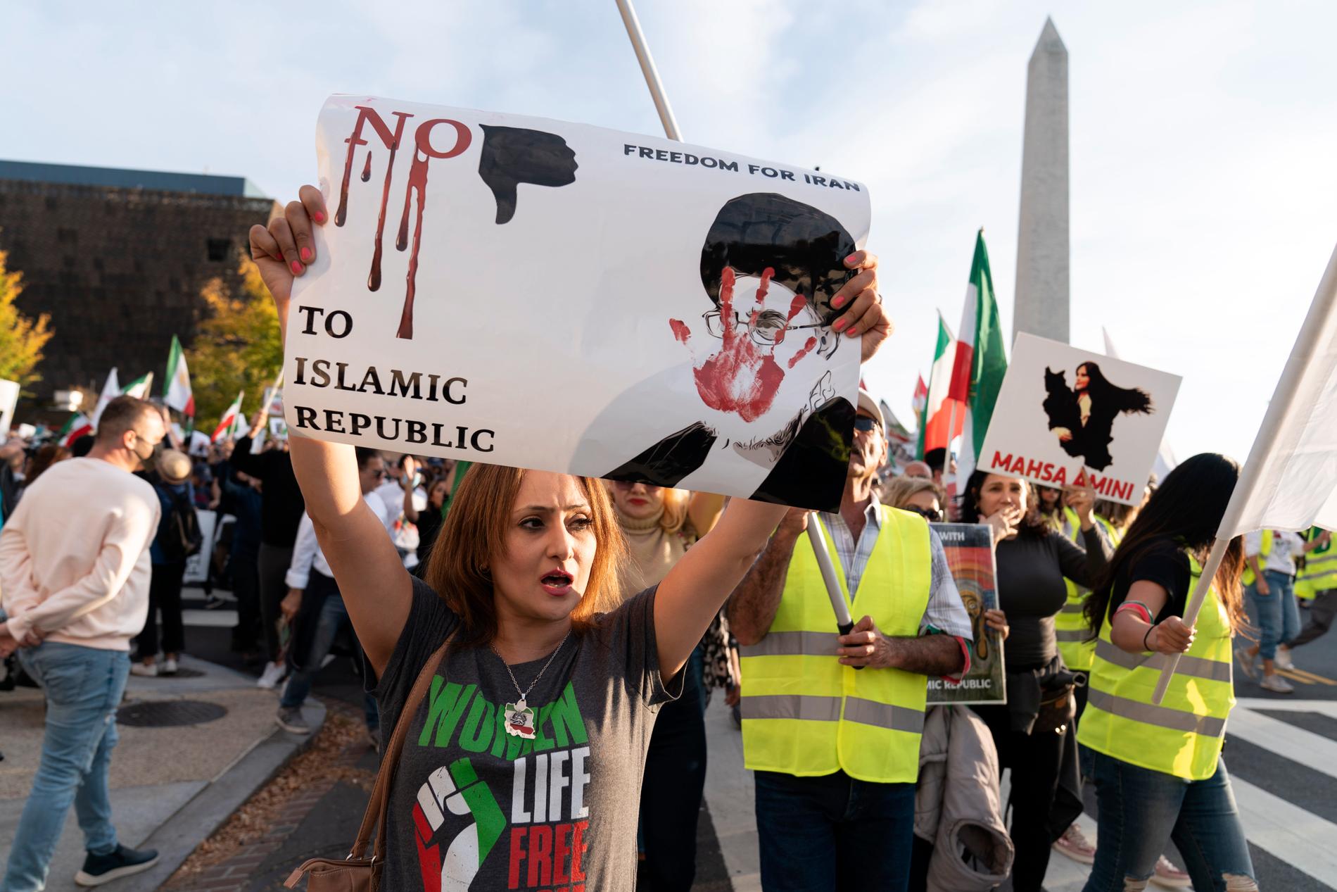 En kvinna håller upp en protestskylt med en bild på Irans president Ebrahim Raisi under en stödprotest i Washington i USA.
