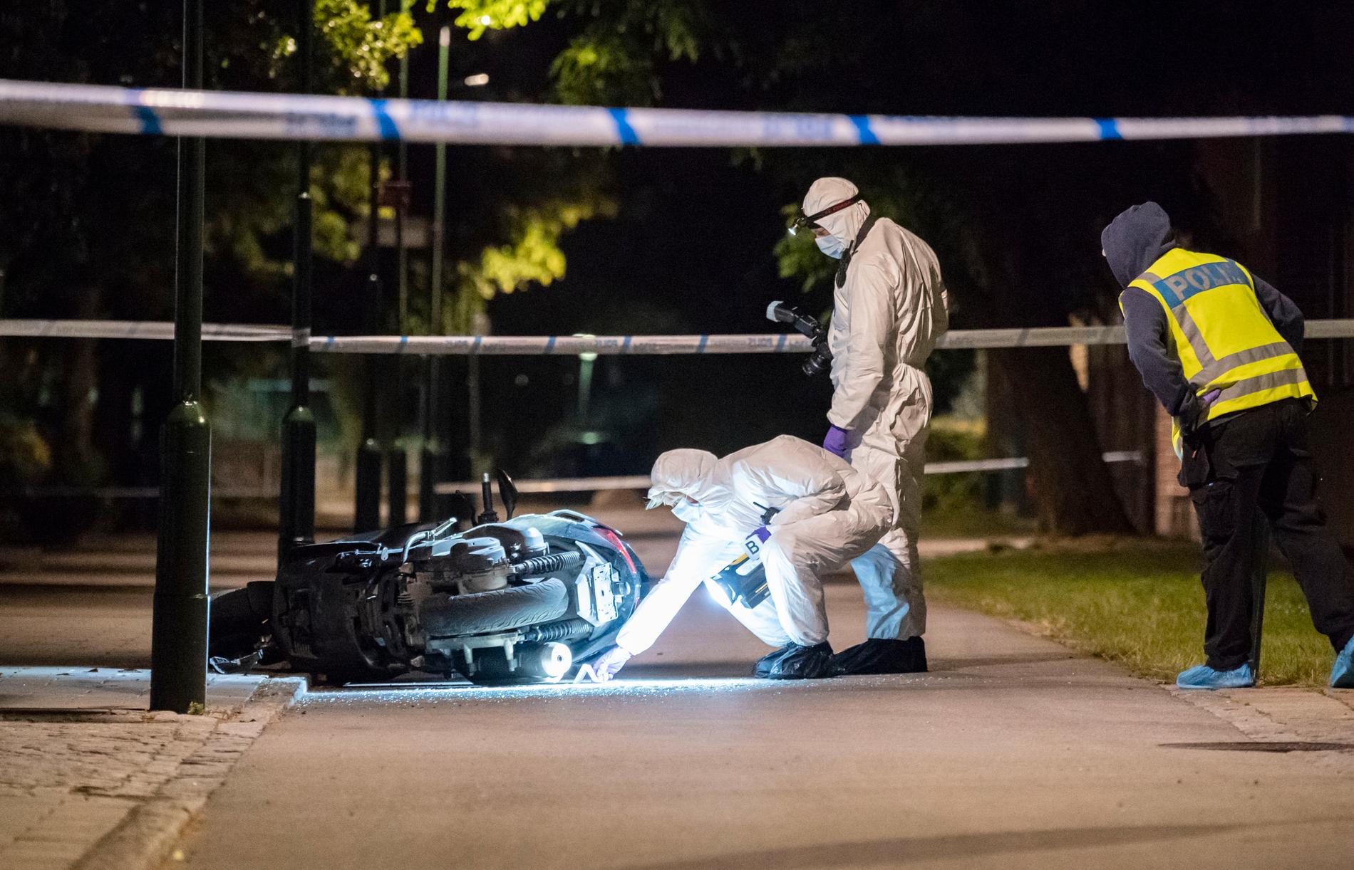 Polisens kriminaltekniker undersöker en moped på en gångbana vid Lindängsplan i Malmö efter det att en man skjutits.