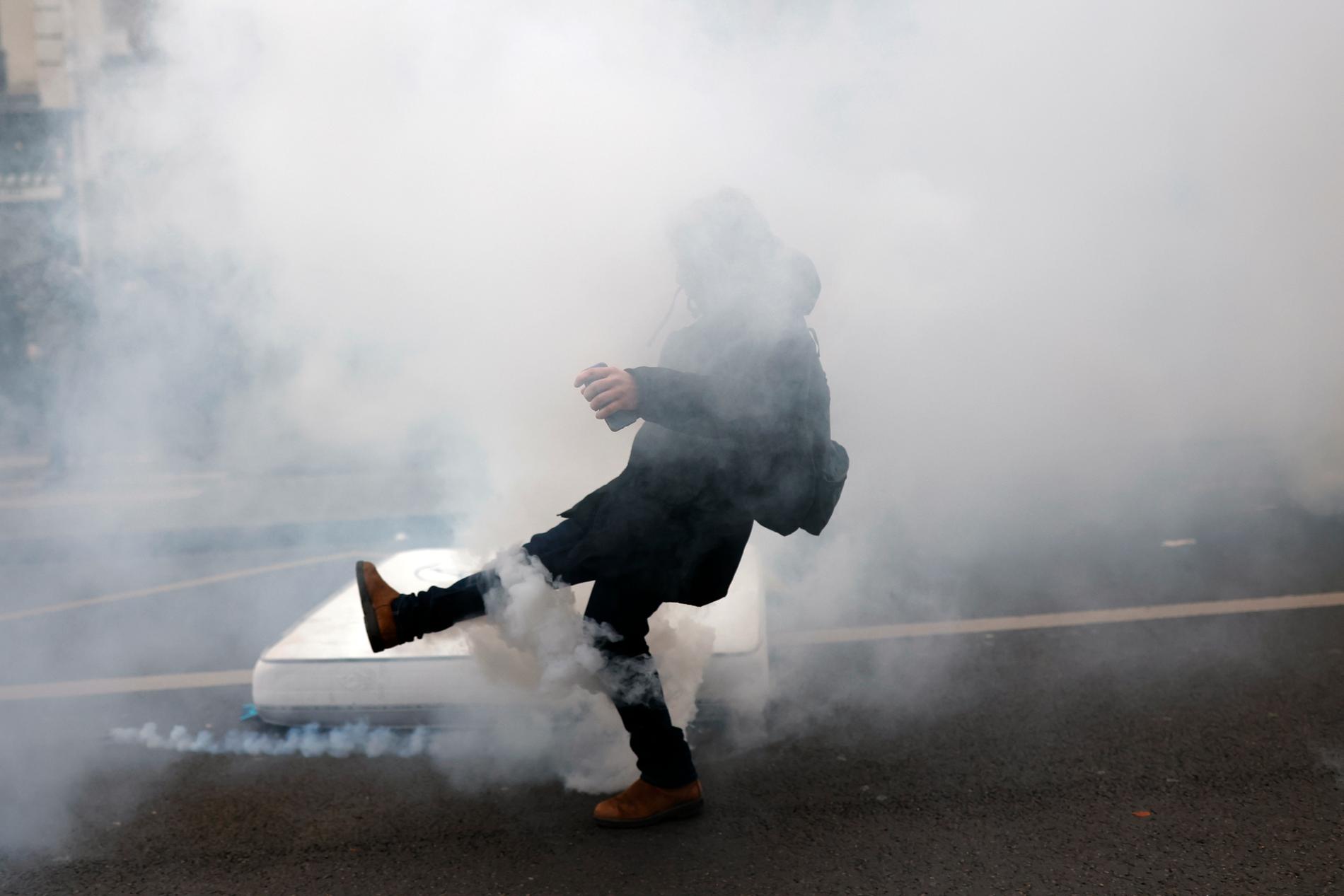 En demonstrant sparkar av tårgasbehållaren under sammandrabbningar vid en demonstration mot planer på att skjuta tillbaka Frankrikes pensionsålder,