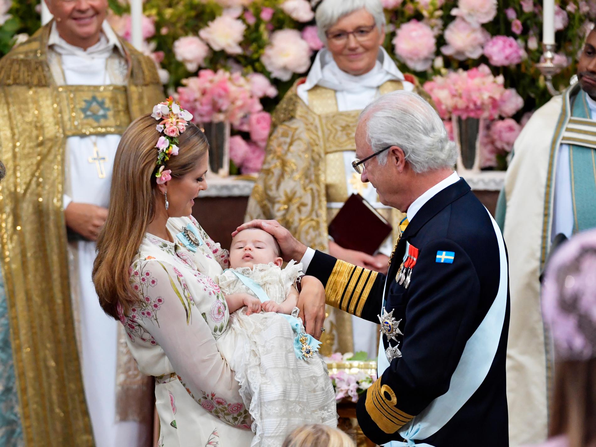 Prinsessan Madeleine håller prinsessan Andrienne och kung Carl Gustaf under dopgudstjänsten för prinisessan