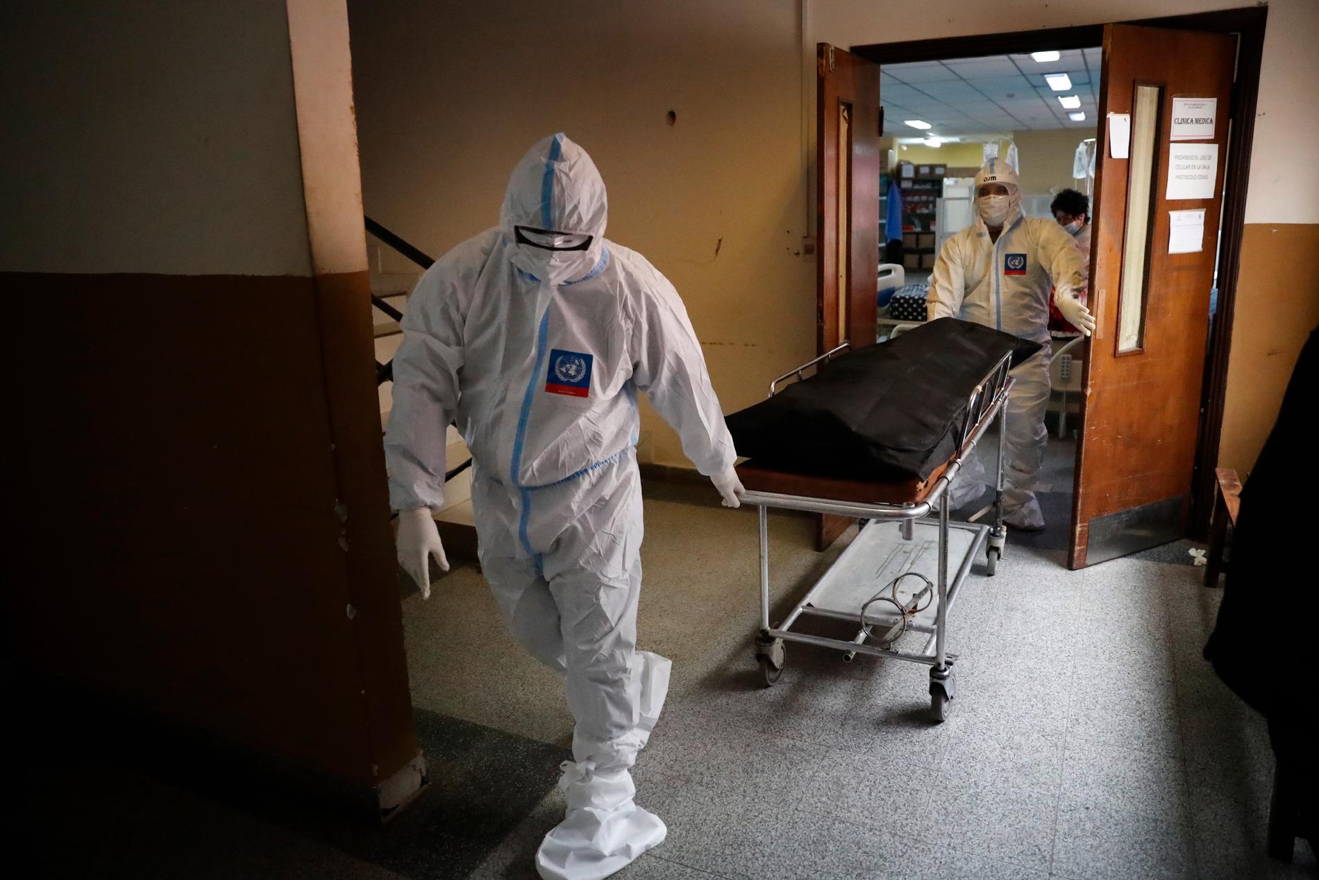 Sköterskor vid ett sjukhus i Paraguay tar bort en sjukhussäng där en kvinna har dött med coronaviruset.